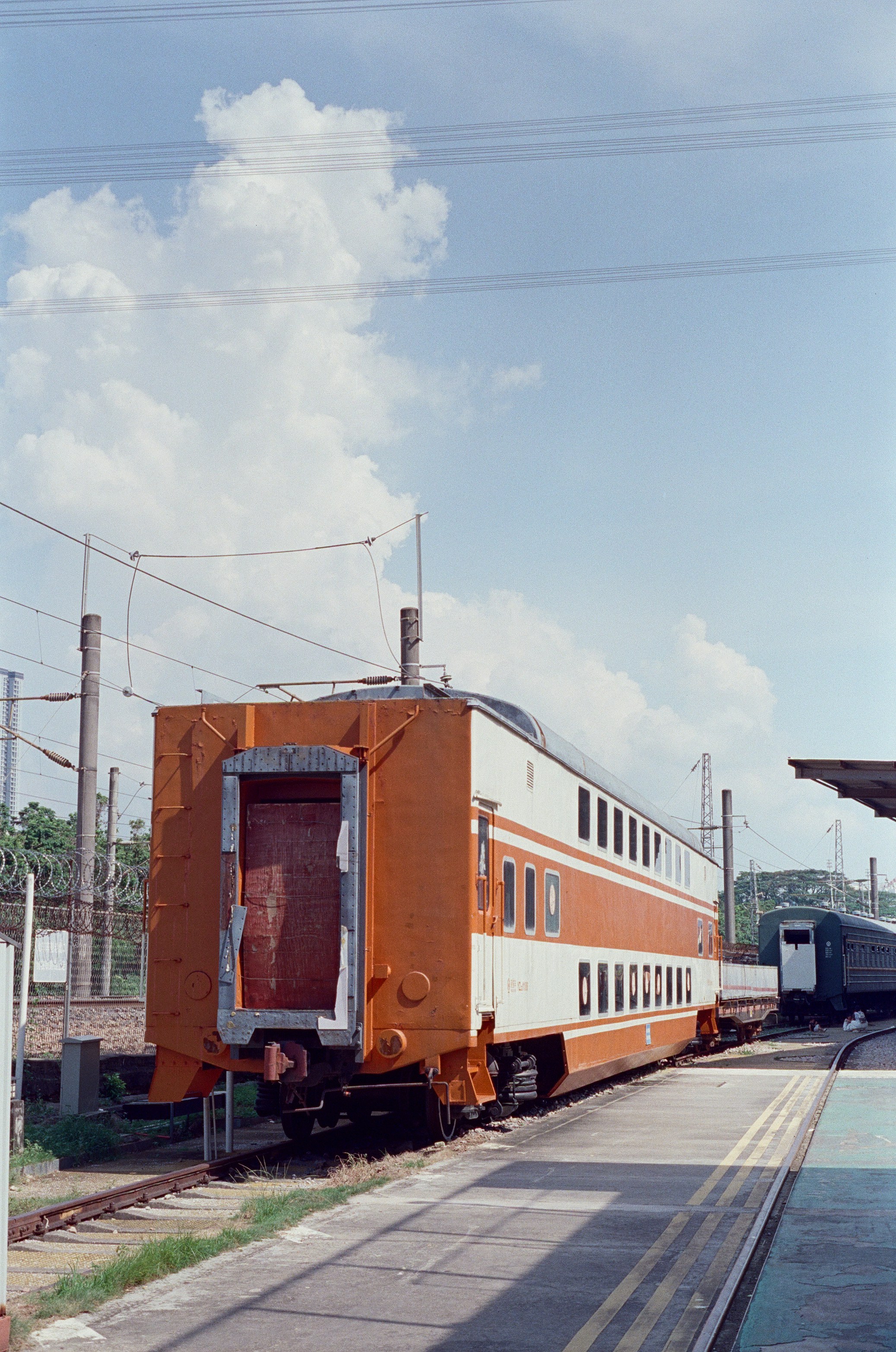 A double-decker orange and white train carriage at a railway station platform.