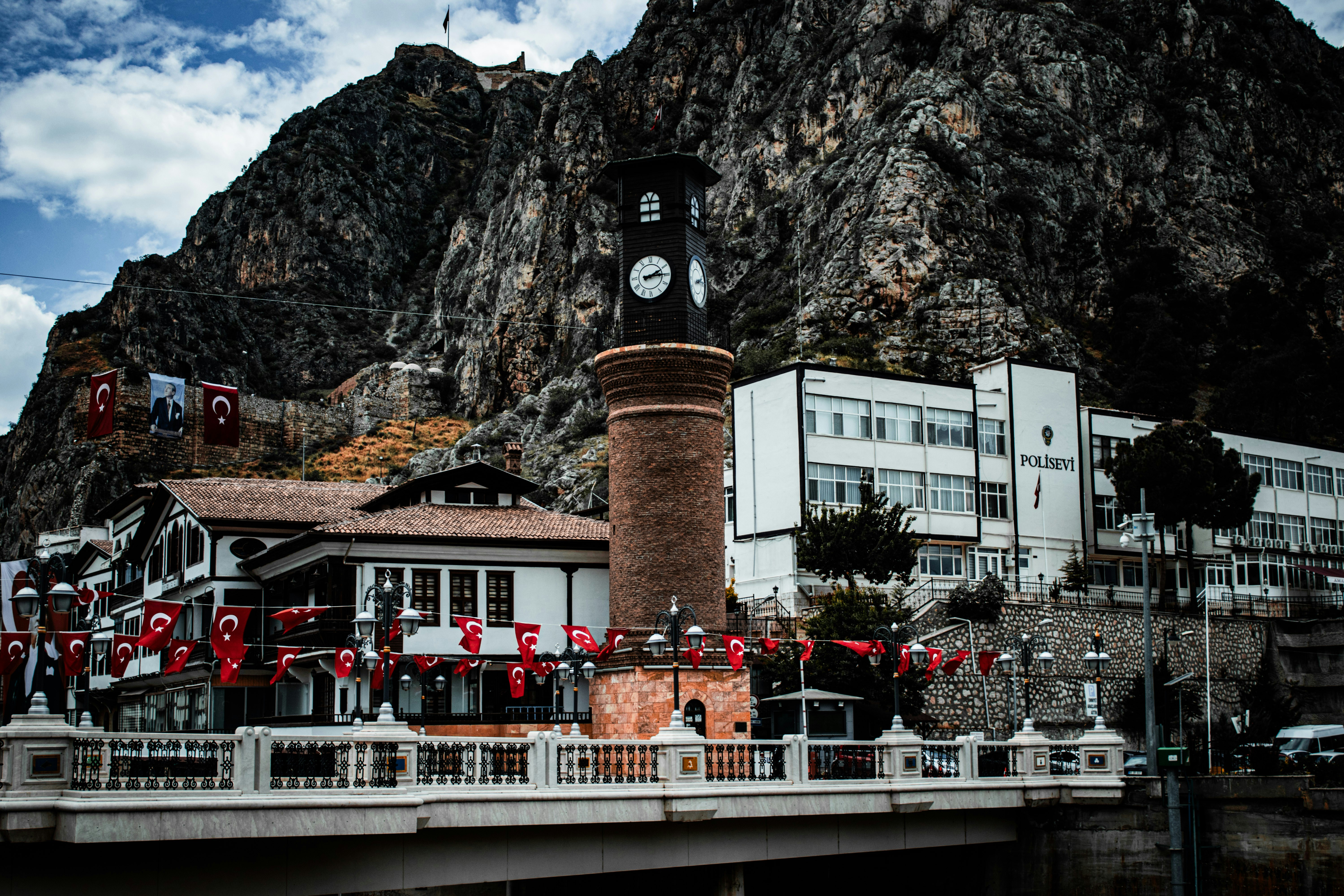A brick clock tower before a rocky mountain in Amasya, Turkey