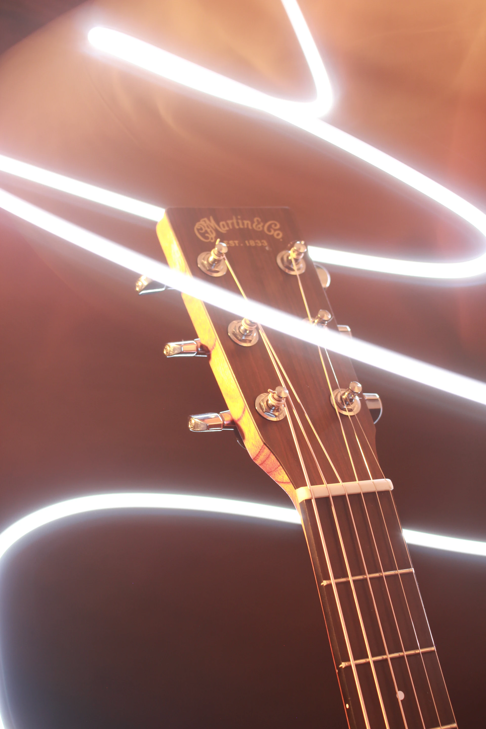 A guitar headstock with light trails swirling in the background