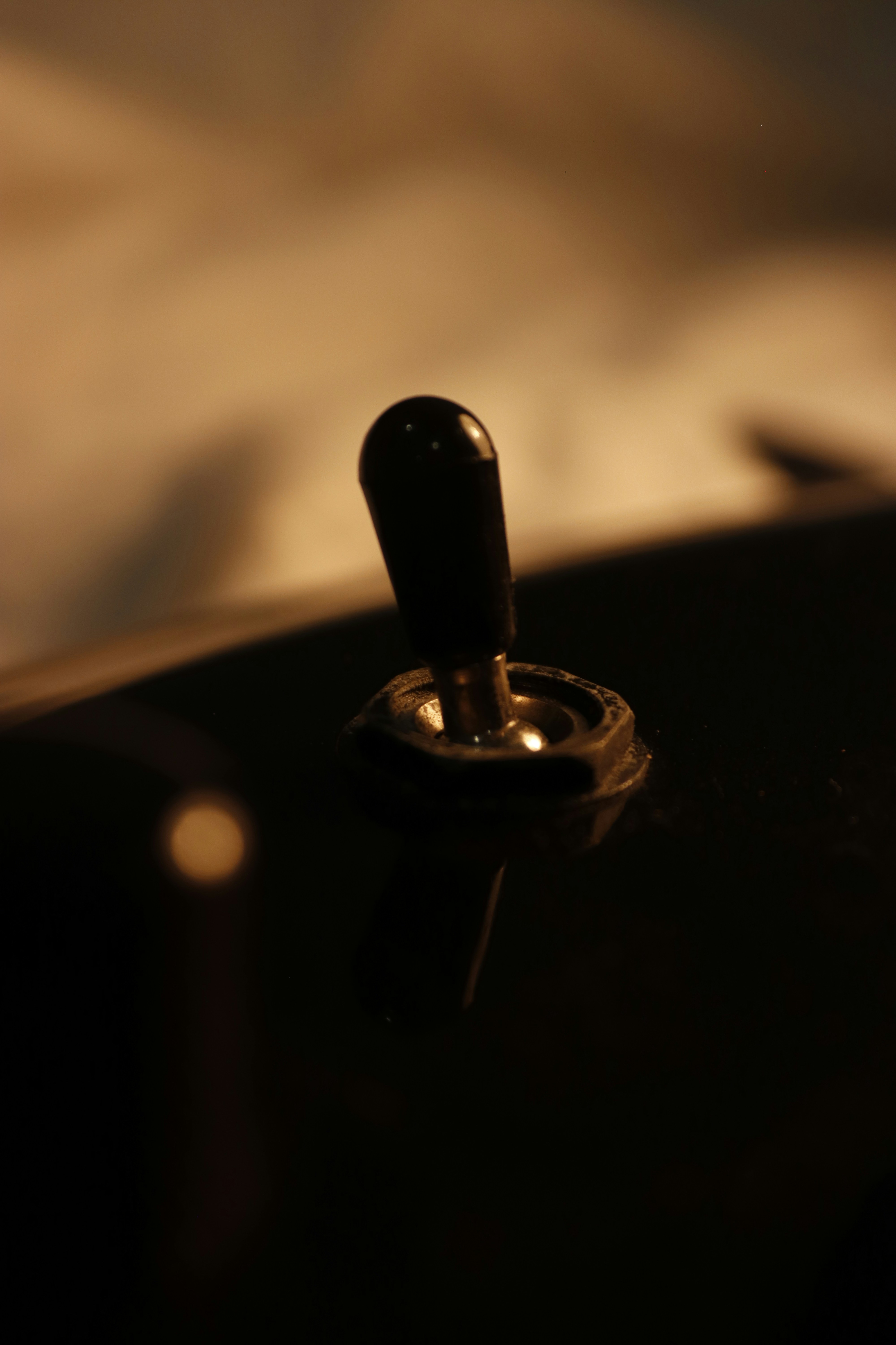 A black toggle switch on a dark surface under warm, dim lighting.