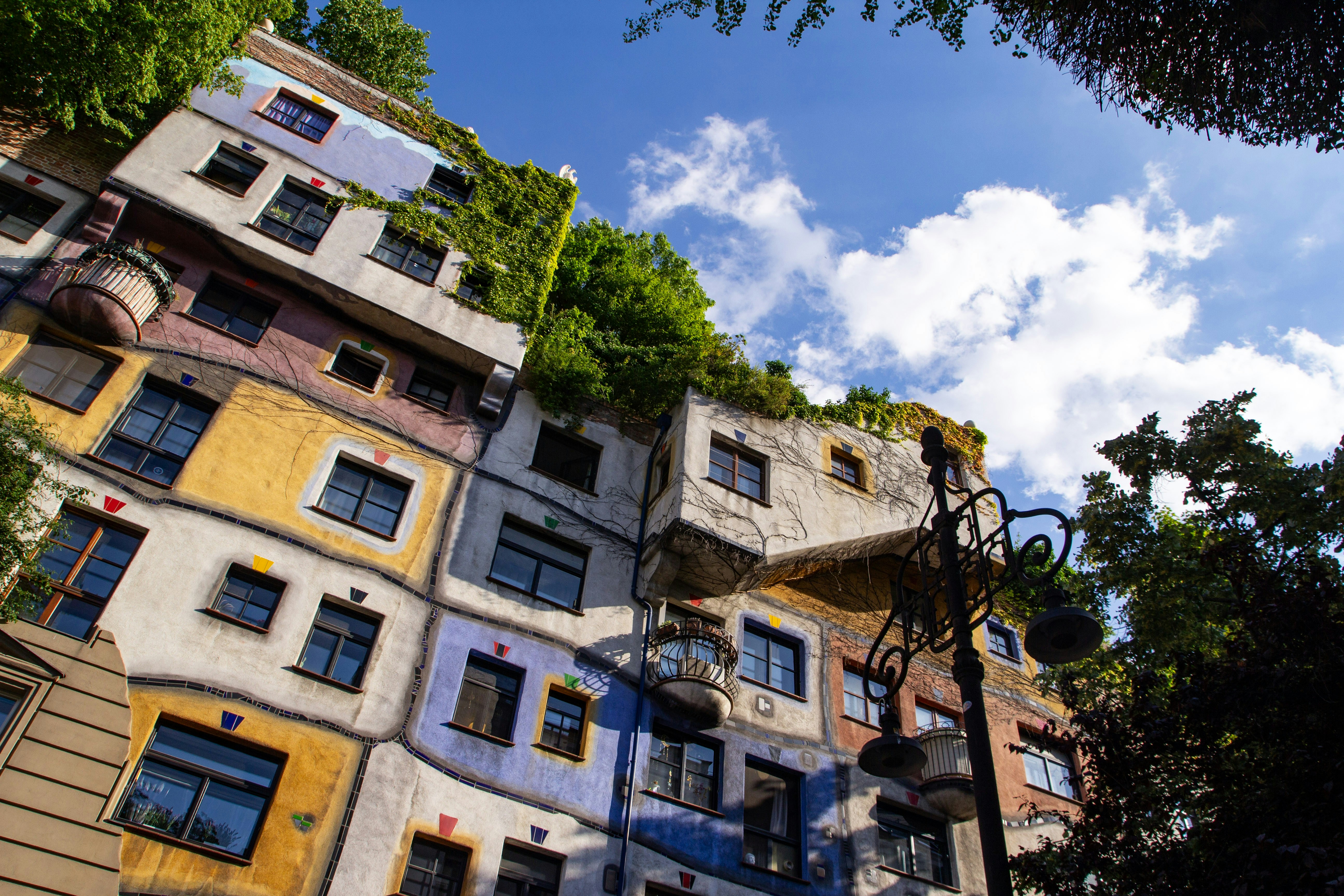 Gedung apartemen Hundertwasserhaus yang penuh warna dengan tanaman hijau di atap di Wina