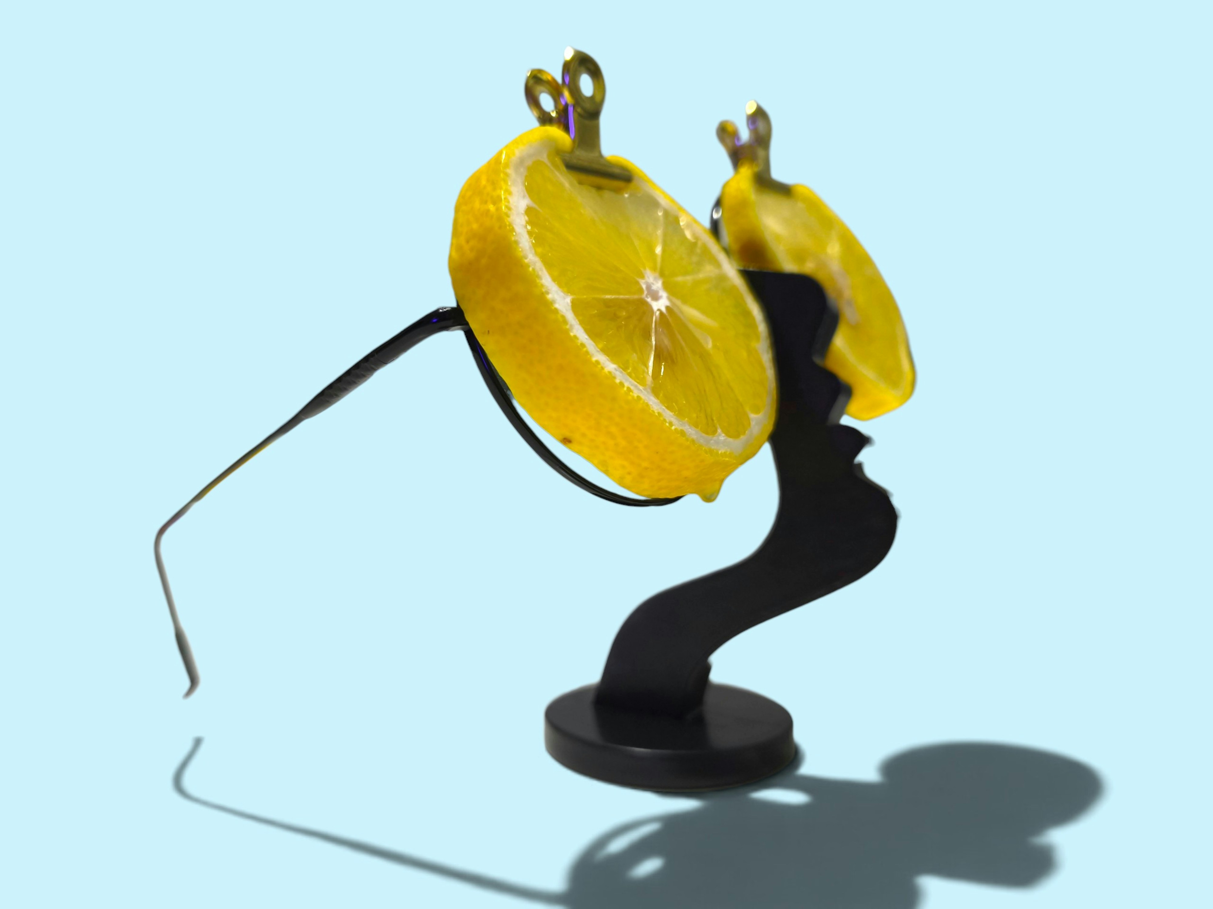 Two lemon slices attached to black eyeglass frames on a black stand