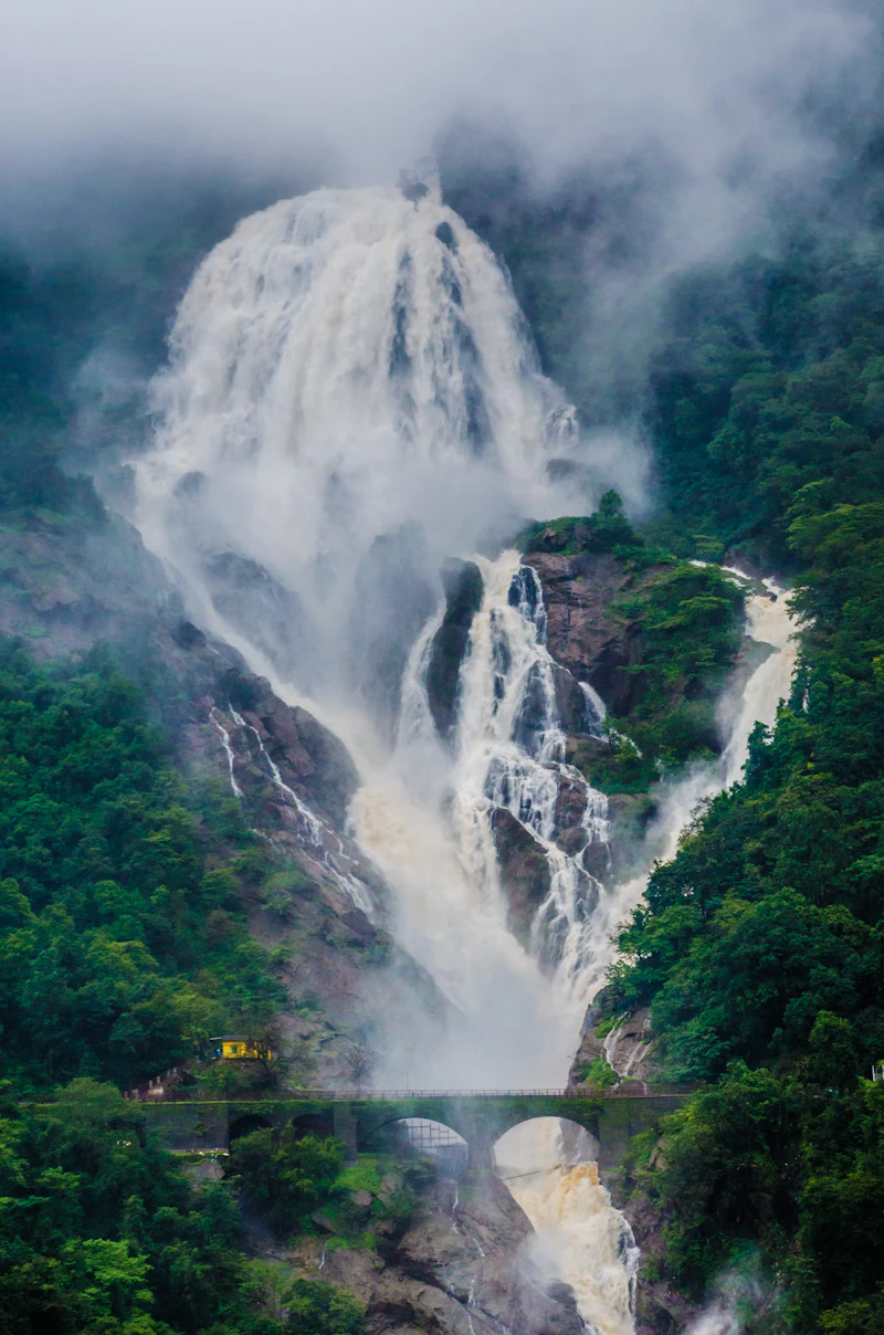 Dudhsagar waterfall in full monsoon flow above a railway bridge