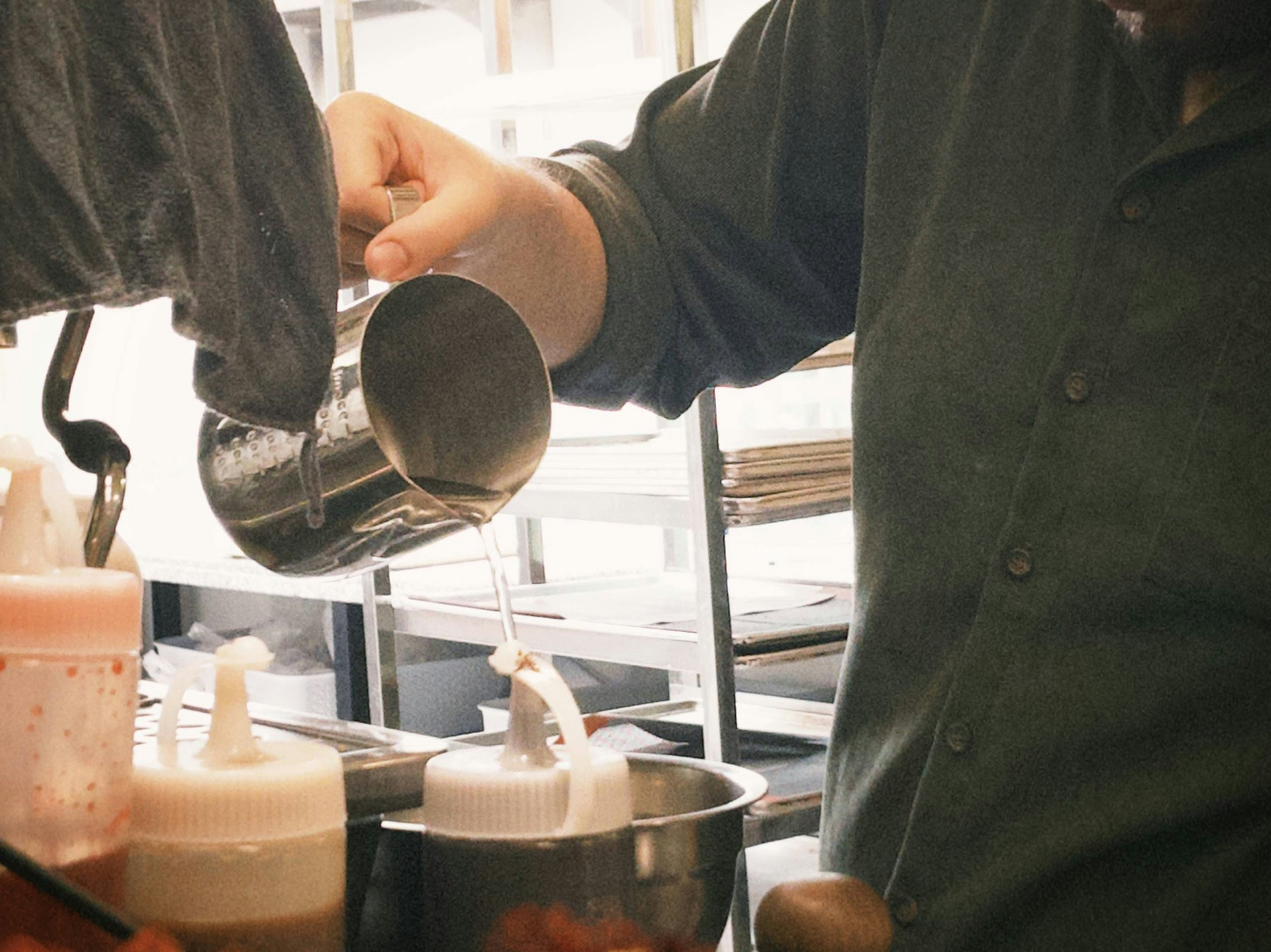 Person pouring steamed milk in a cafe