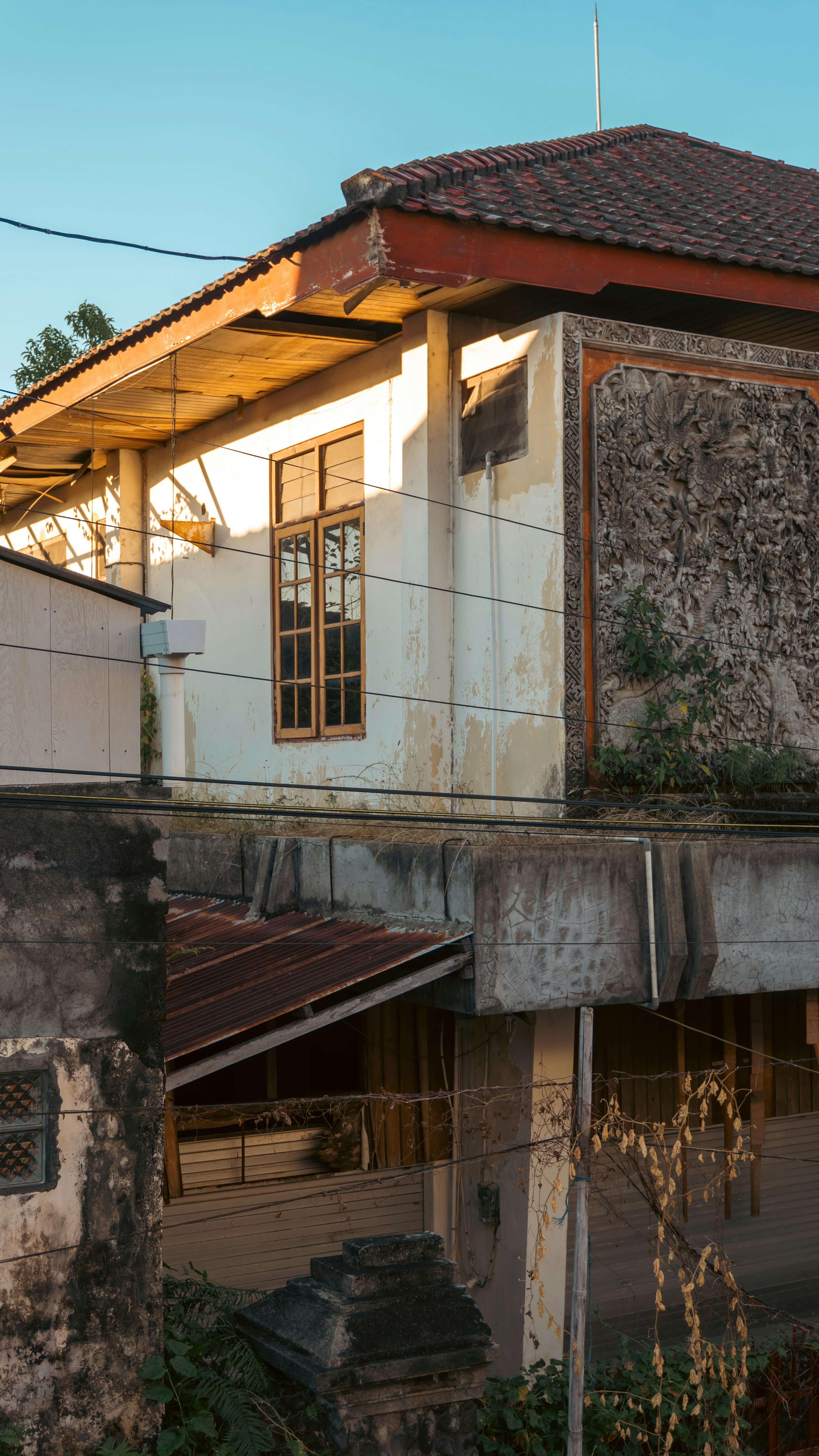 A weathered building with a stone relief carving and a tiled roof at sunset