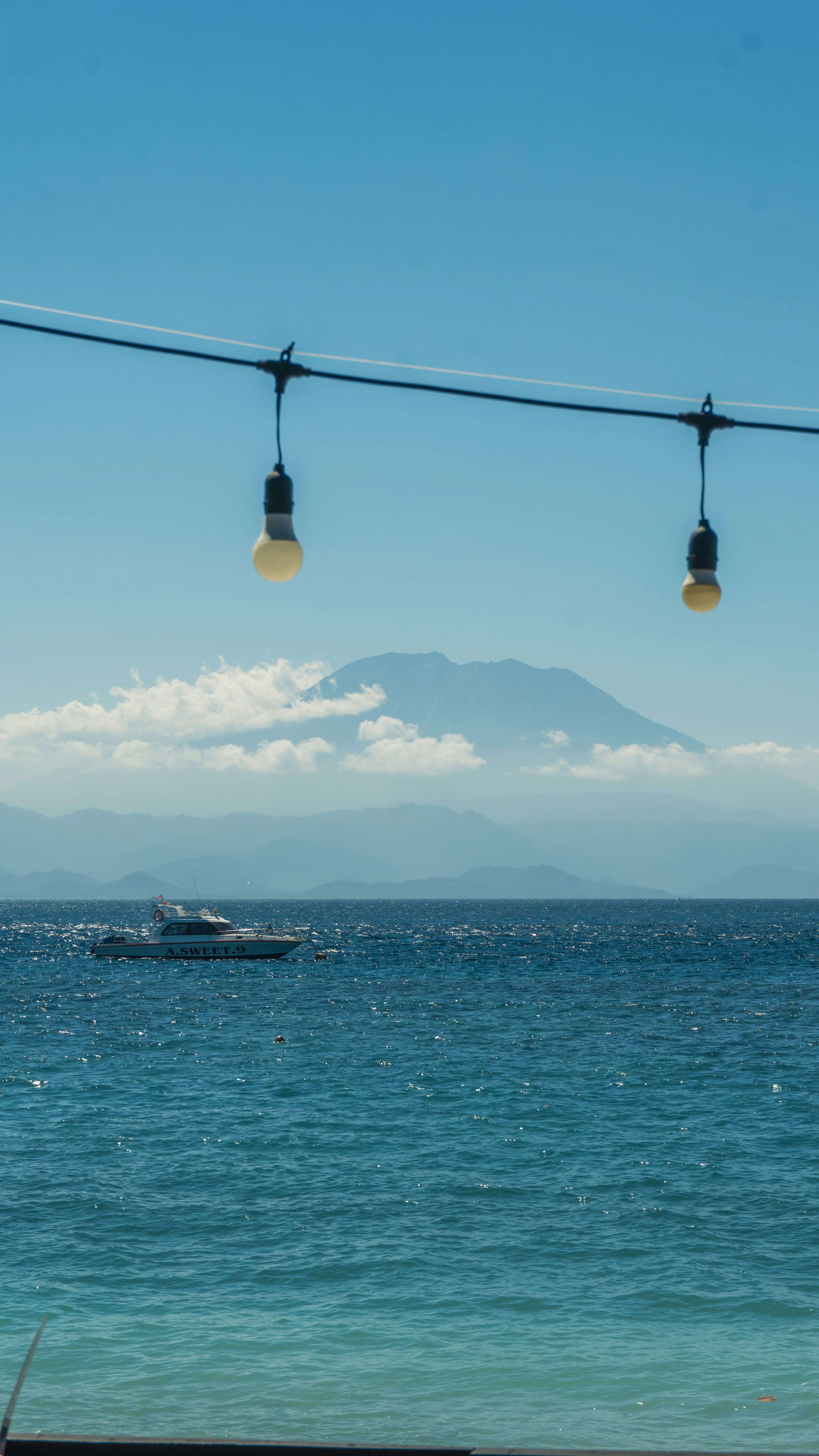A motorboat on the blue sea with a distant mountain under a clear sky