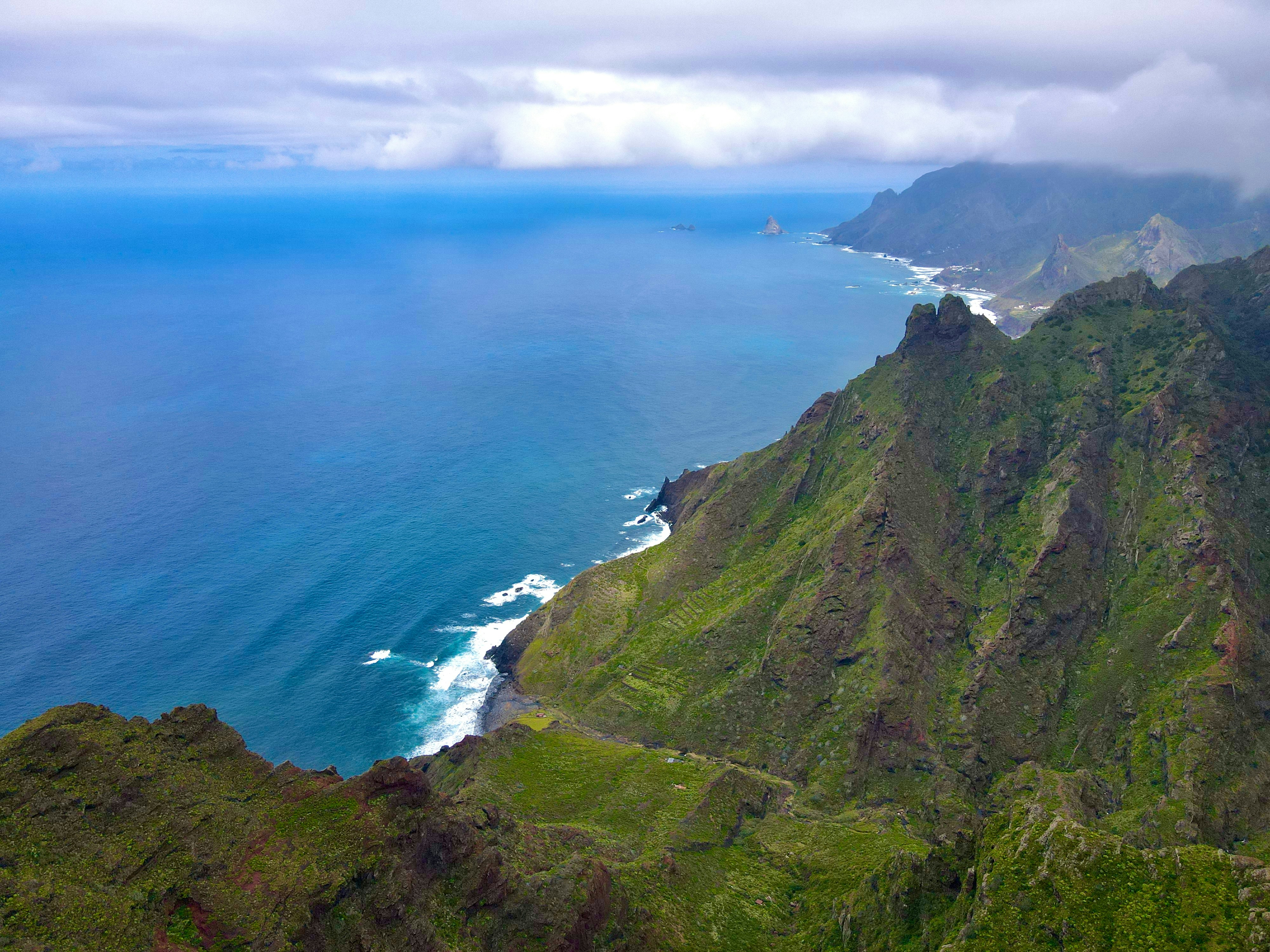 A steep green mountain ridge dropping into the deep blue ocean