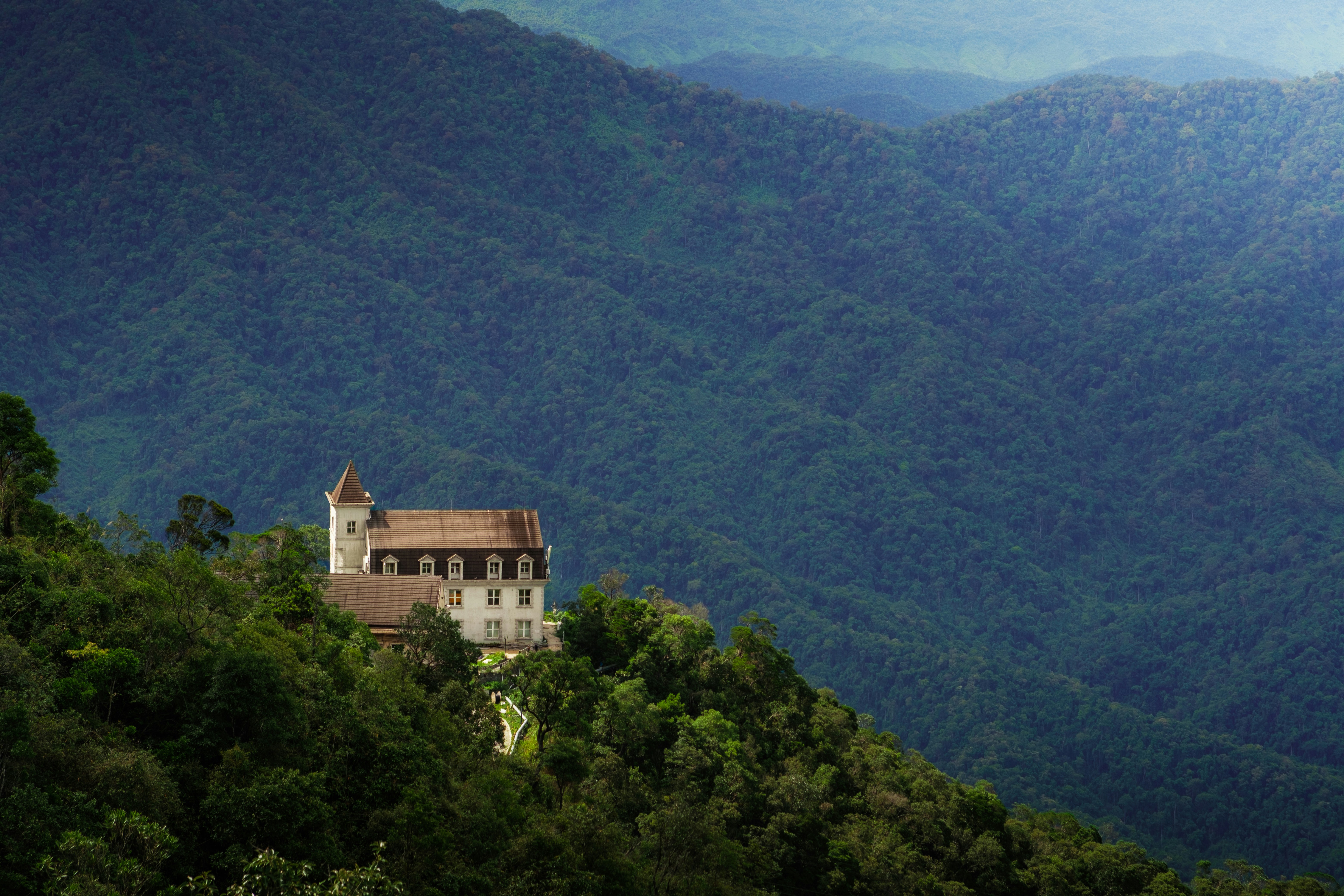 A large building with a tower on a forested mountain ridge