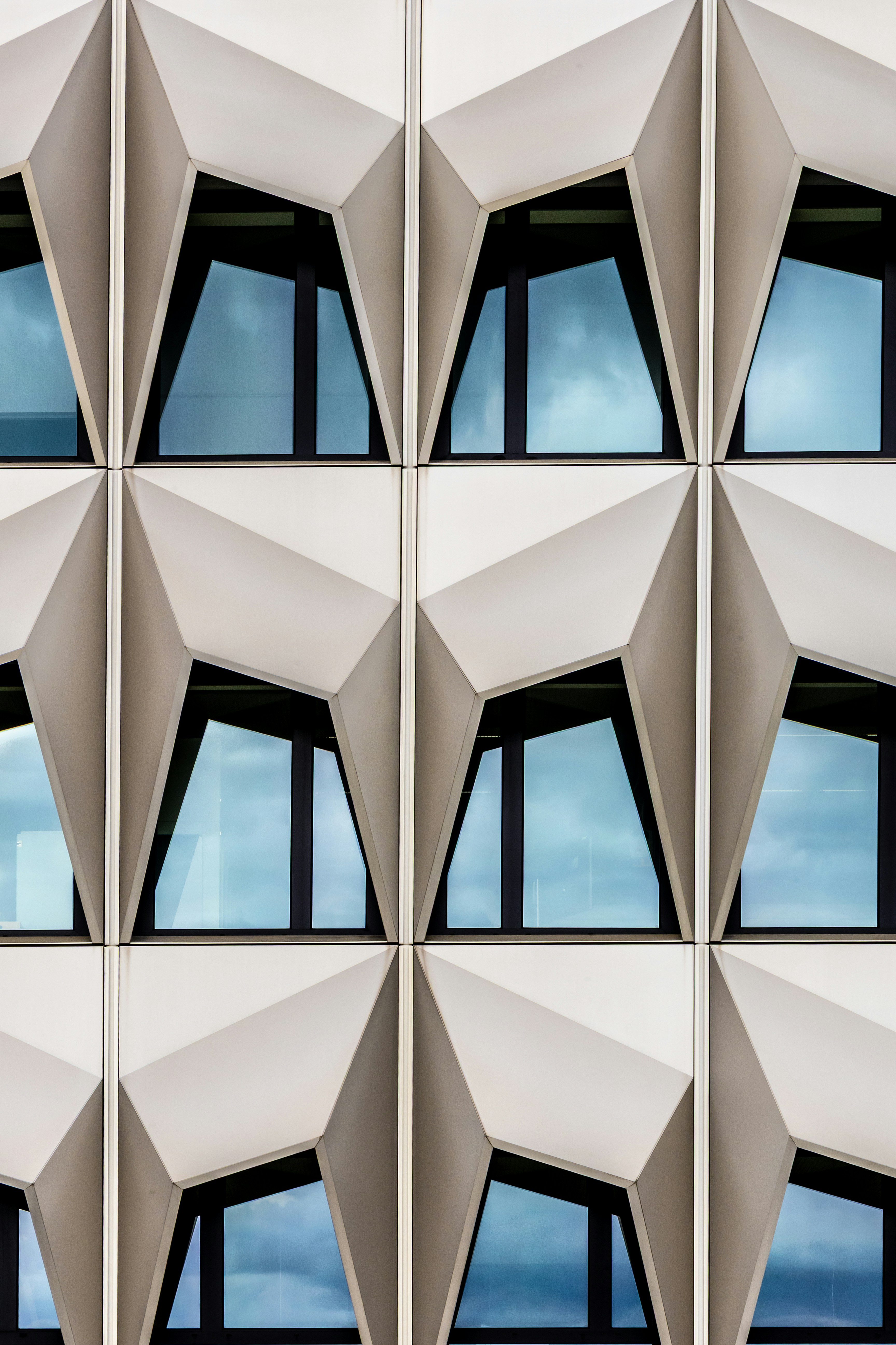 Une façade moderne avec des panneaux blancs géométriques et des fenêtres en verre réfléchissant