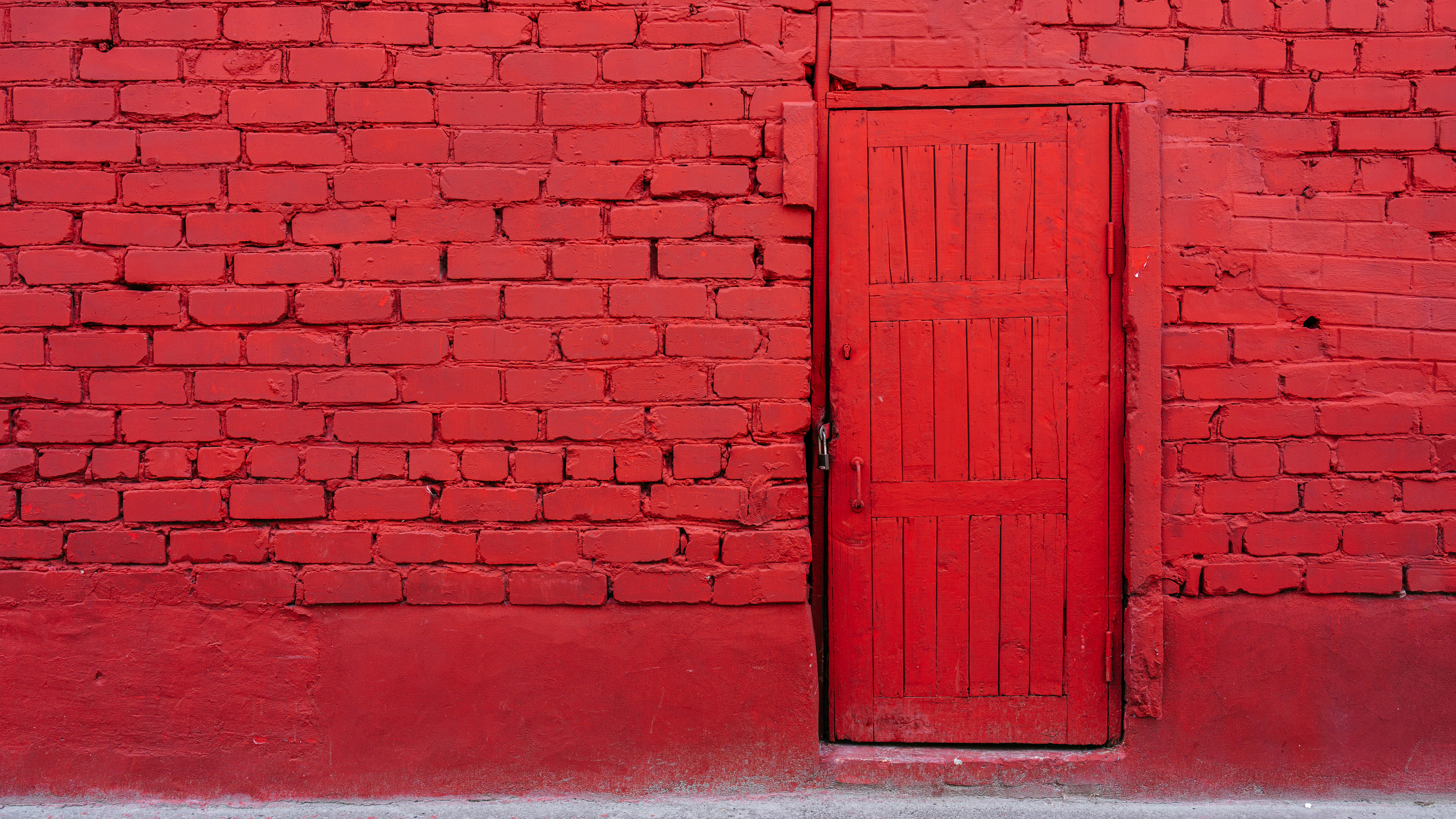 Une porte en bois rouge vif encastrée dans un mur de briques rouges assorti
