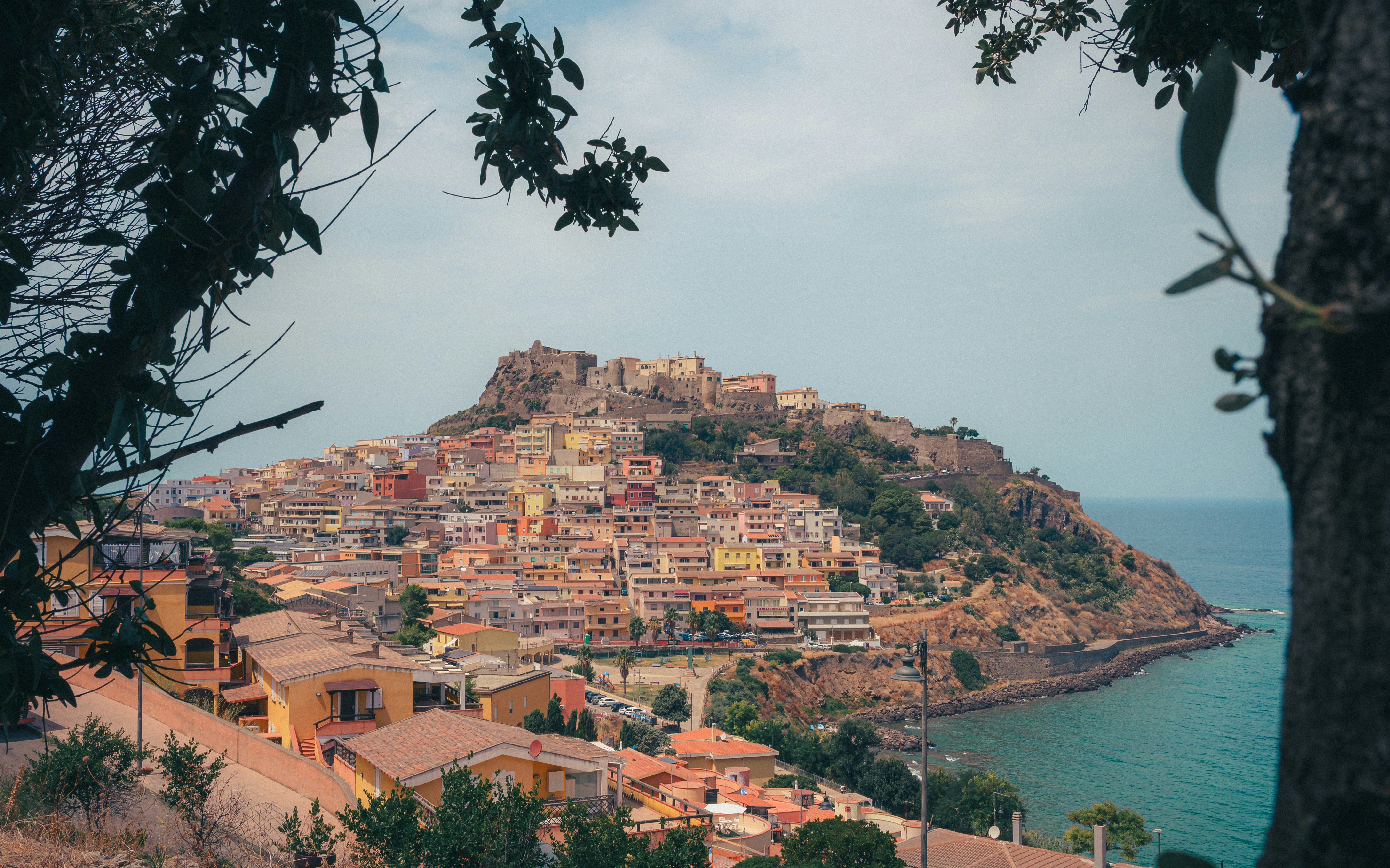 A hillside town with colorful buildings overlooking the sea in Castelsardo, Sardinia | Houfy — Book Direct