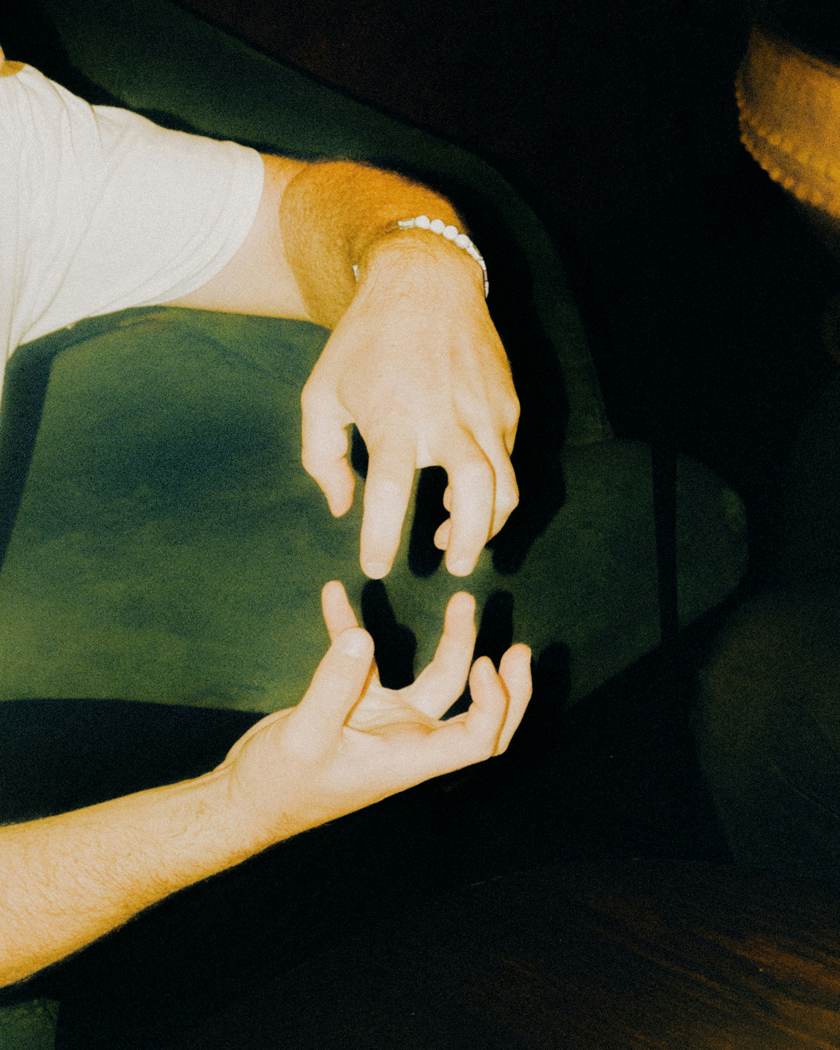 Two hands with fingers curved toward each other in a dark, warm-toned setting. - 相关推荐