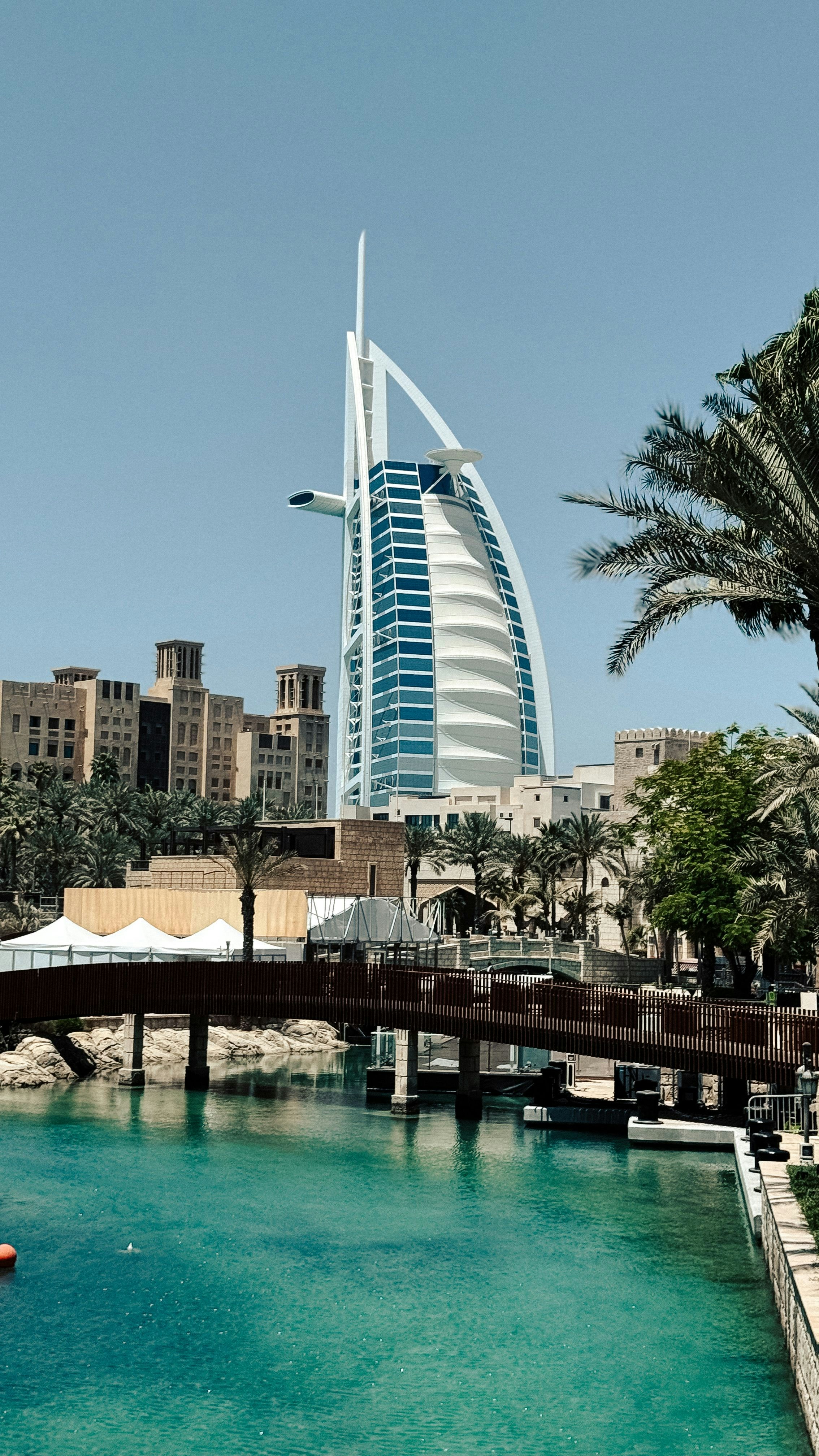 The Burj Al Arab hotel rising above palm trees and a canal in Dubai
