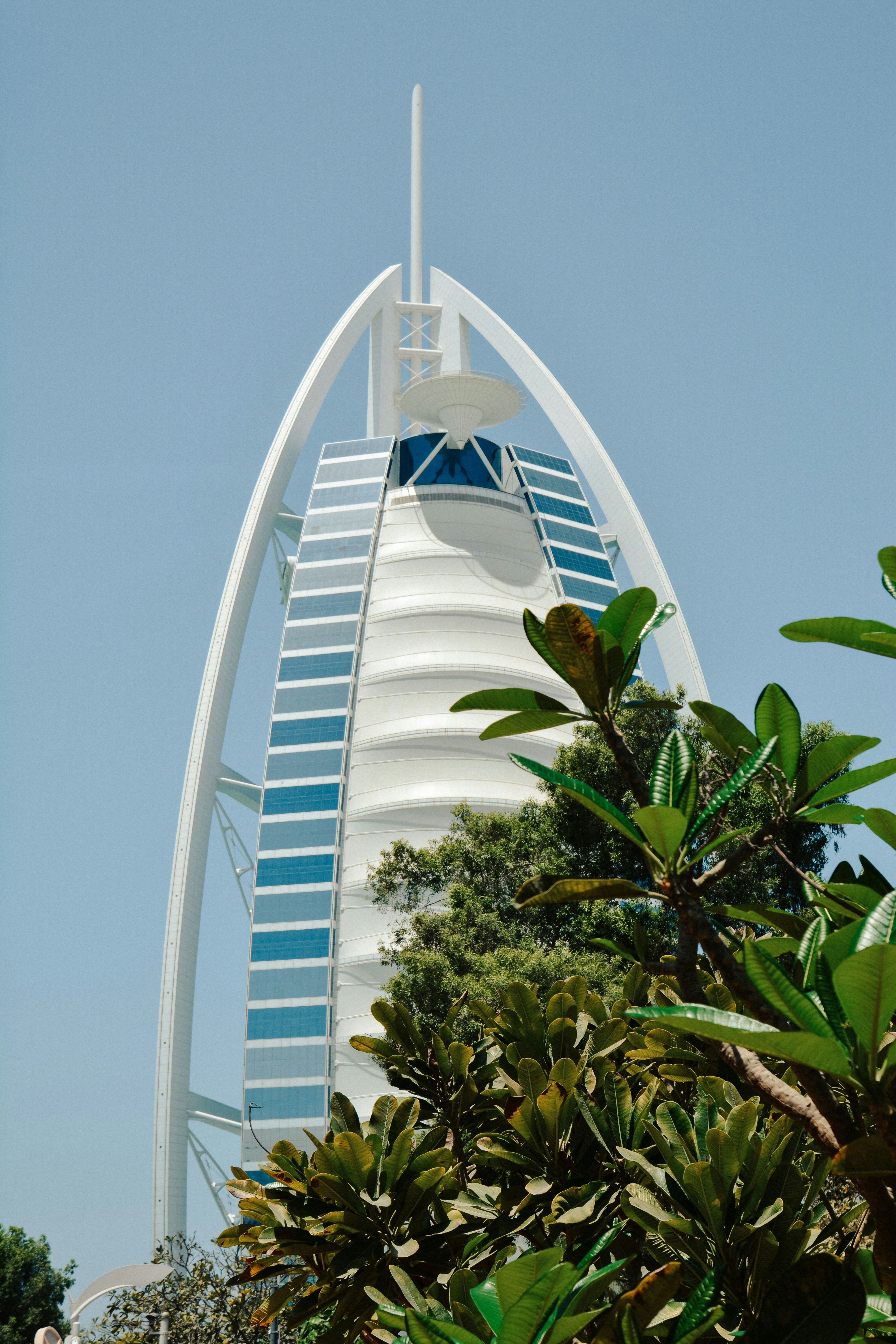 The Burj Al Arab hotel rising behind green trees in Dubai, United Arab Emirates
