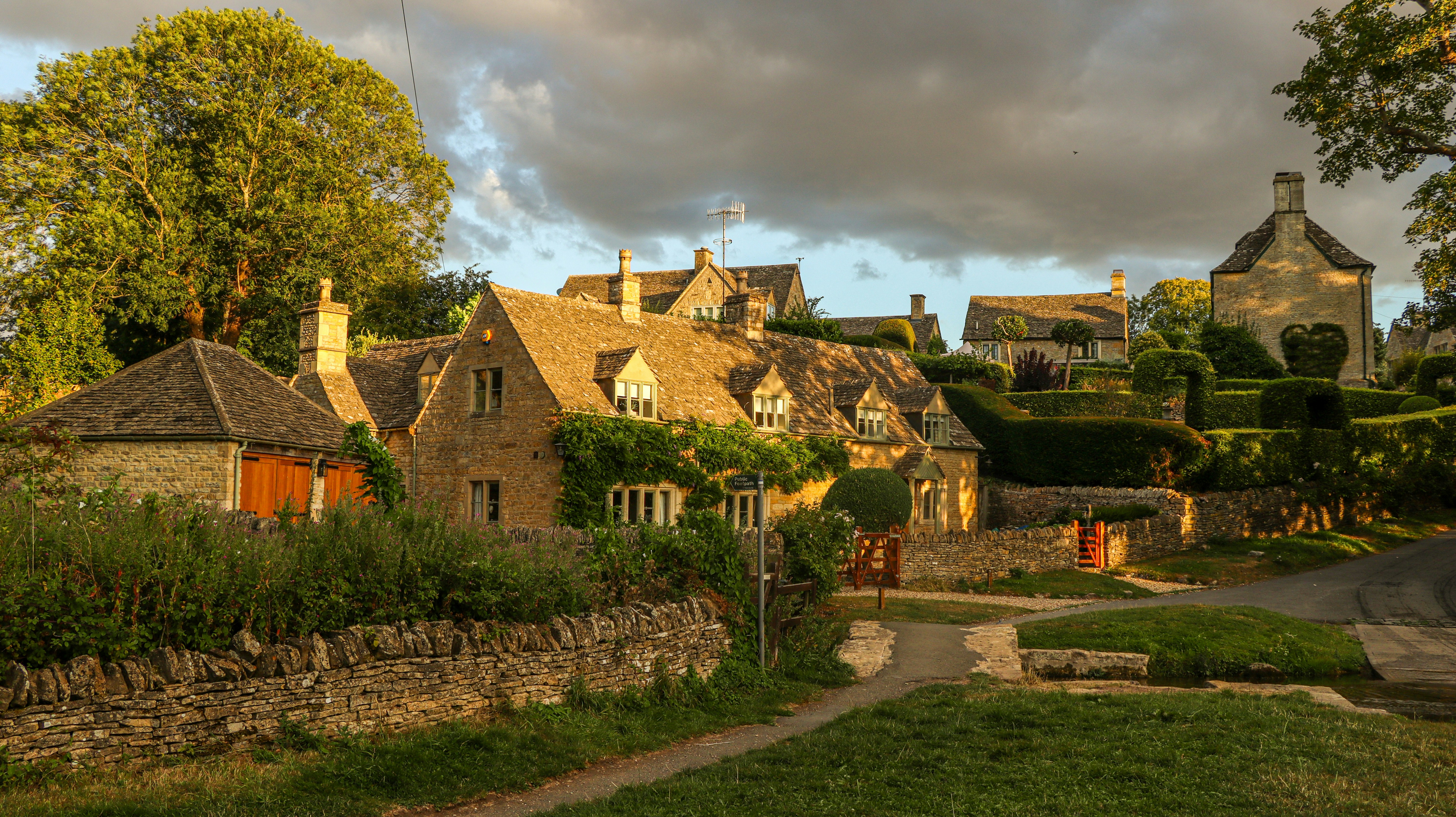 Steinhütten mit kletternden Ranken im Dorf Castle Combe zur goldenen Stunde