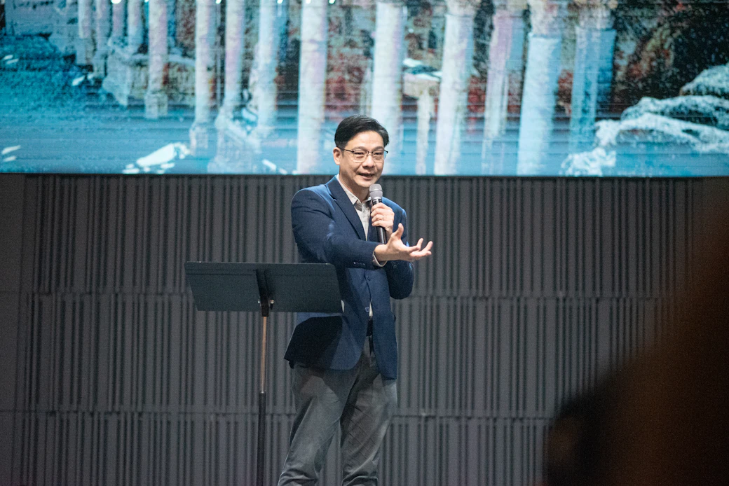 남색 재킷 차림으로 무대에서 강연하는 연자