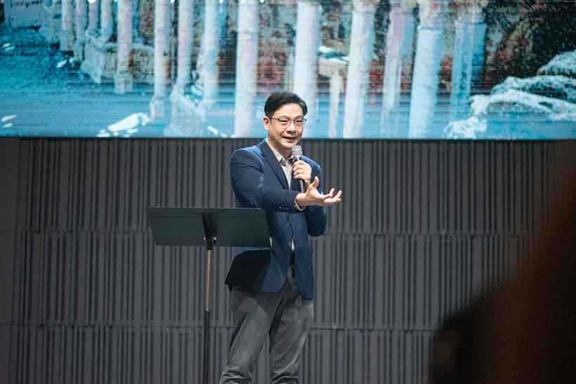 남색 재킷 차림으로 무대에서 강연하는 연자