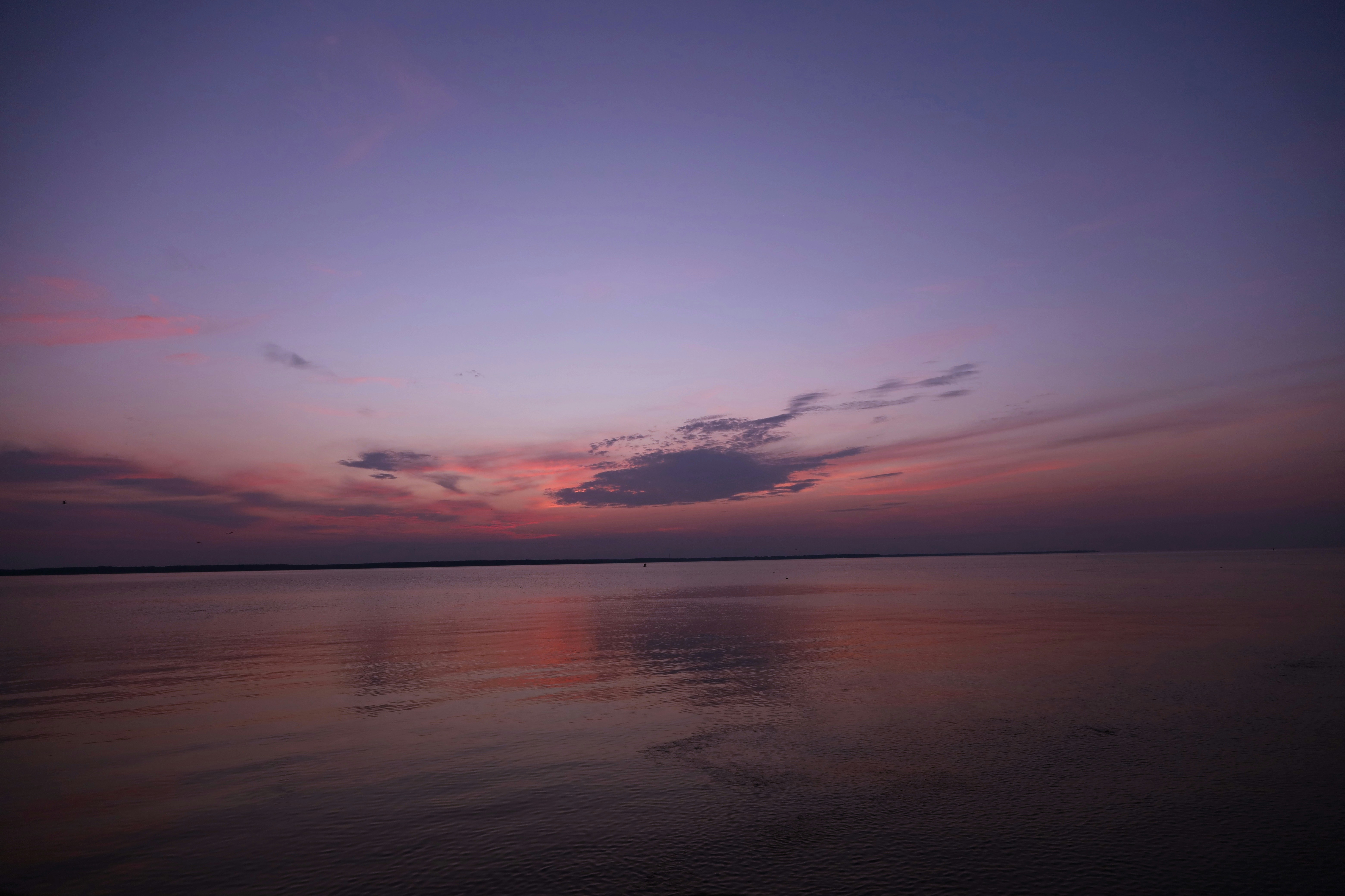 Un plan d’eau calme reflétant un ciel violet et rose dans une faible lumière.