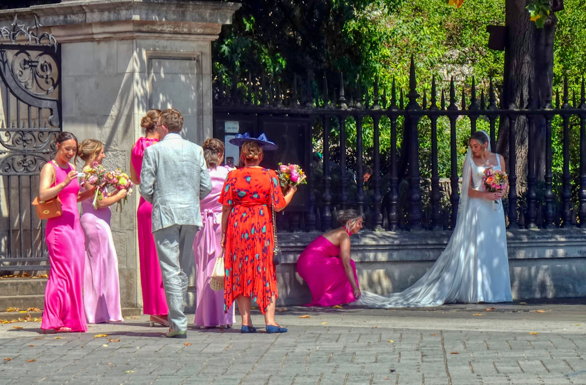 Wedding guests in bright pink, coral and red dresses outside a wedding venue
