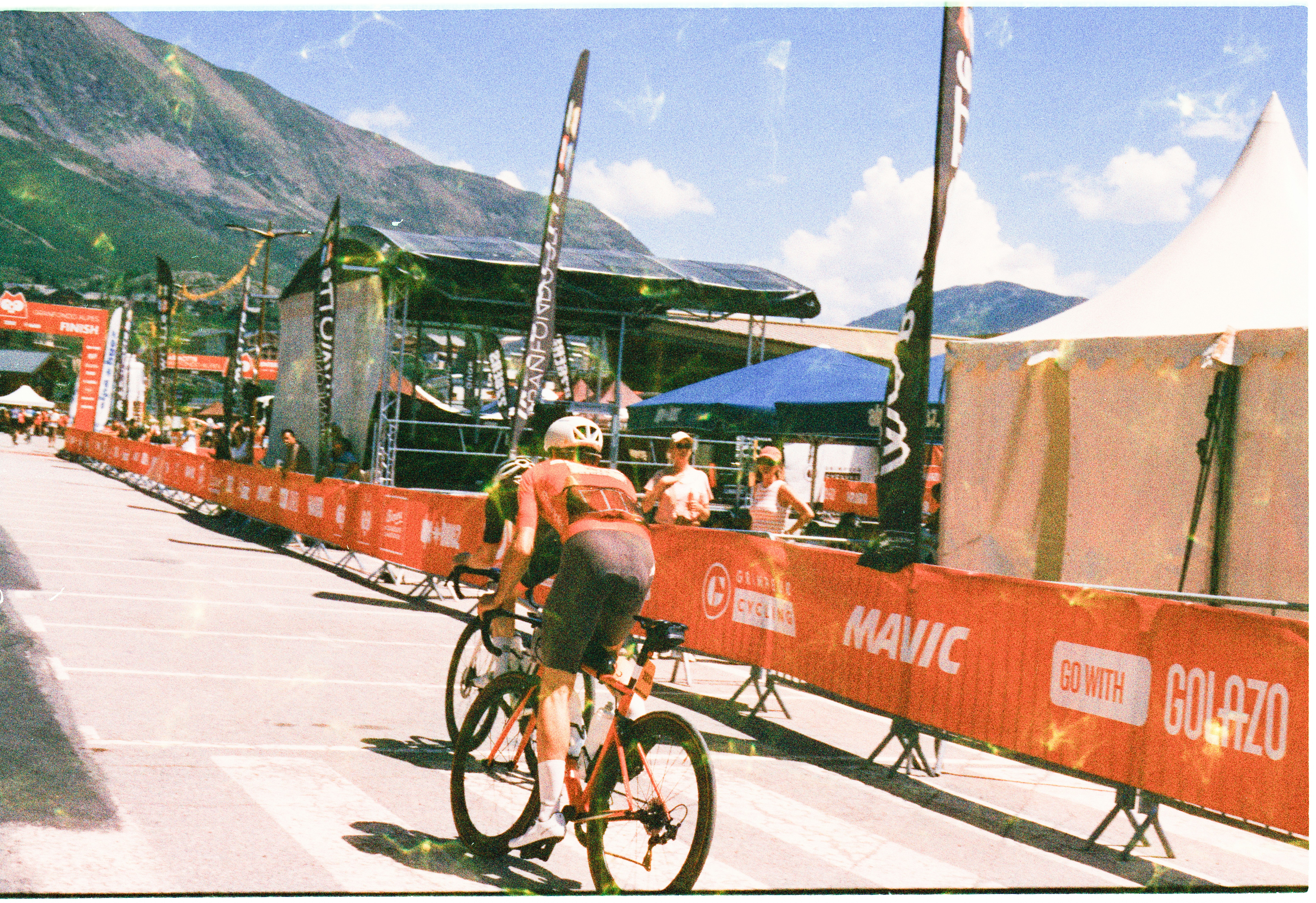 A cyclist riding past red barriers at a mountain cycling event finish line