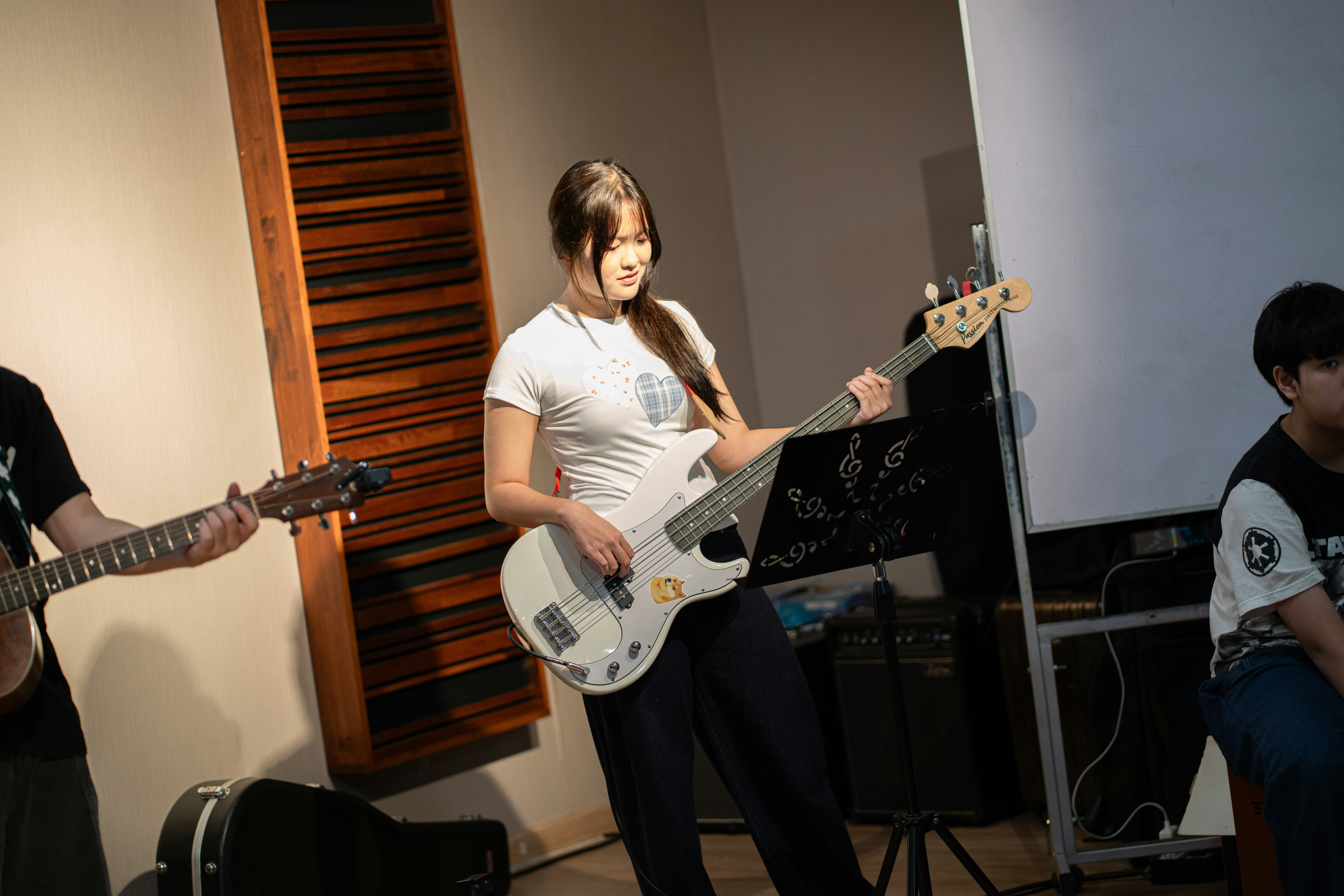 A guitar teacher showing a teenage student a chord shape in a colourful studio room