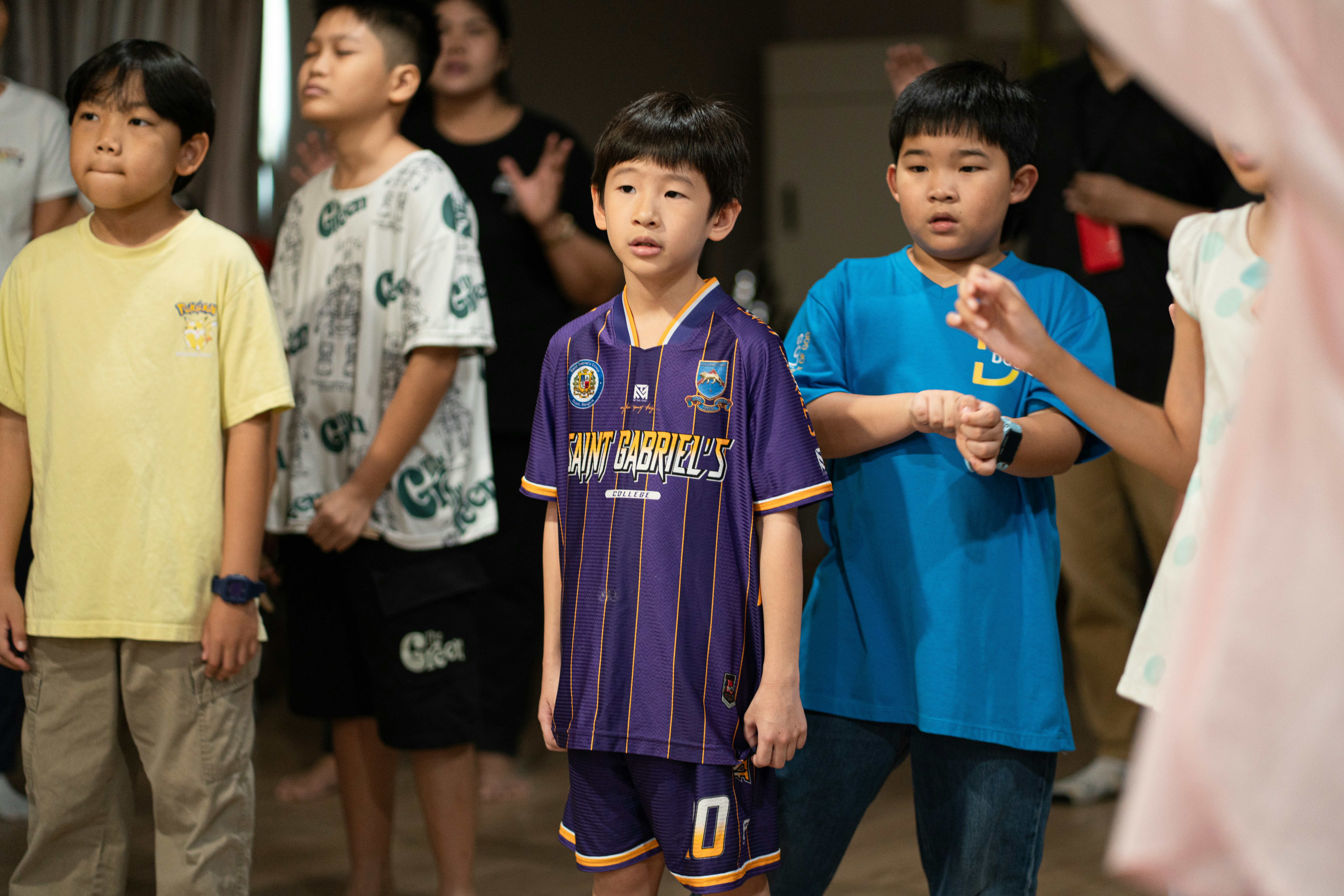 A group of children in colorful t-shirts and a sports uniform standing together.