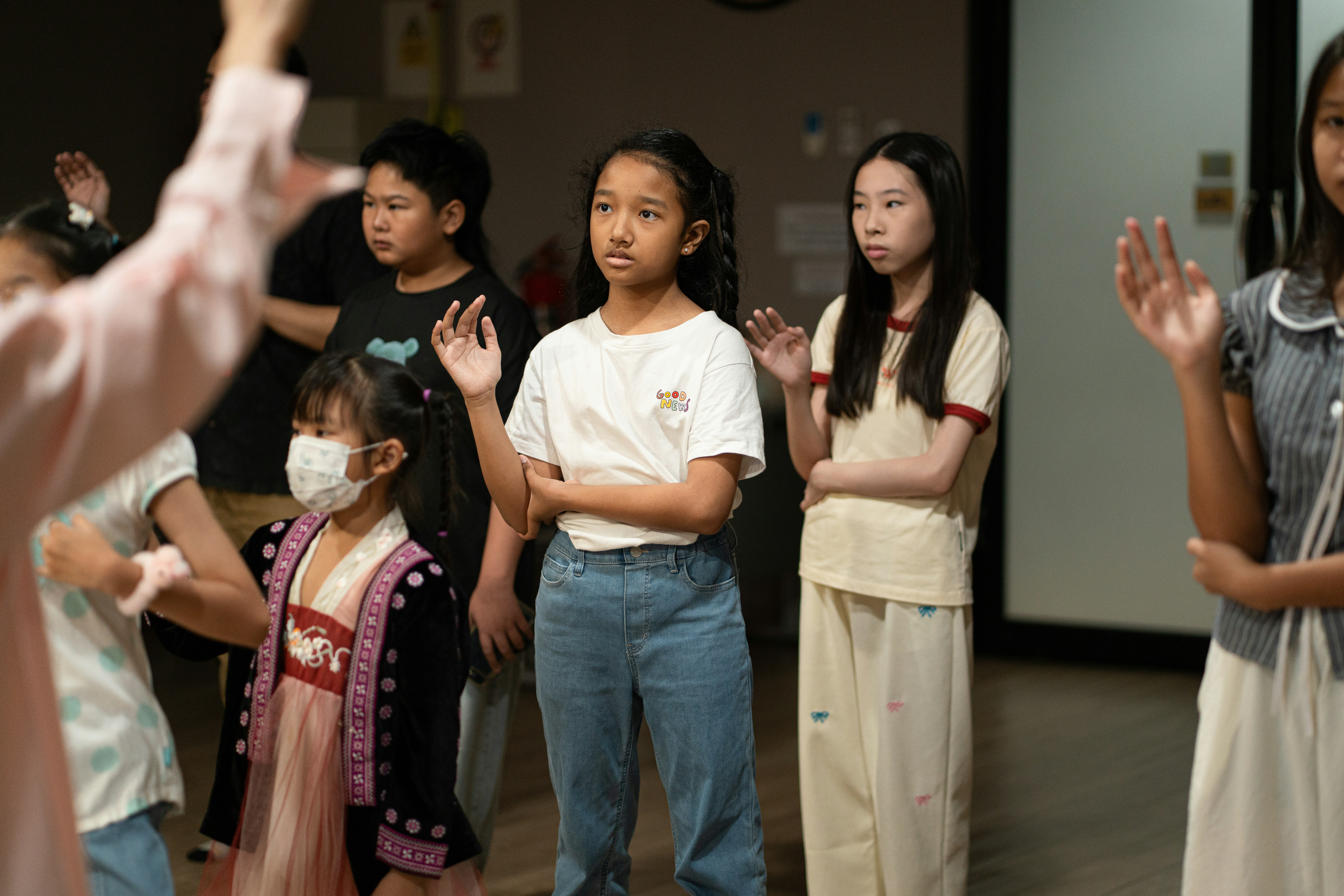 A group of children raising their hands in a classroom setting.