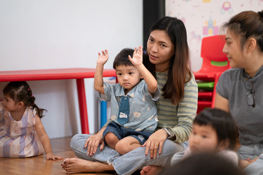 A teacher celebrates with a laughing child, arms raised