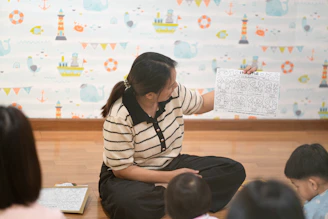 A woman holding a worksheet for children in a room with nautical wallpaper