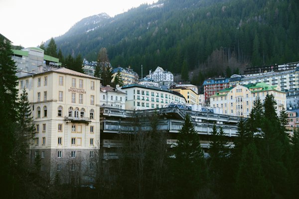 Buildings and a concrete structure nestled against a dense pine forest on a mountain — Bad Gastein, Austria