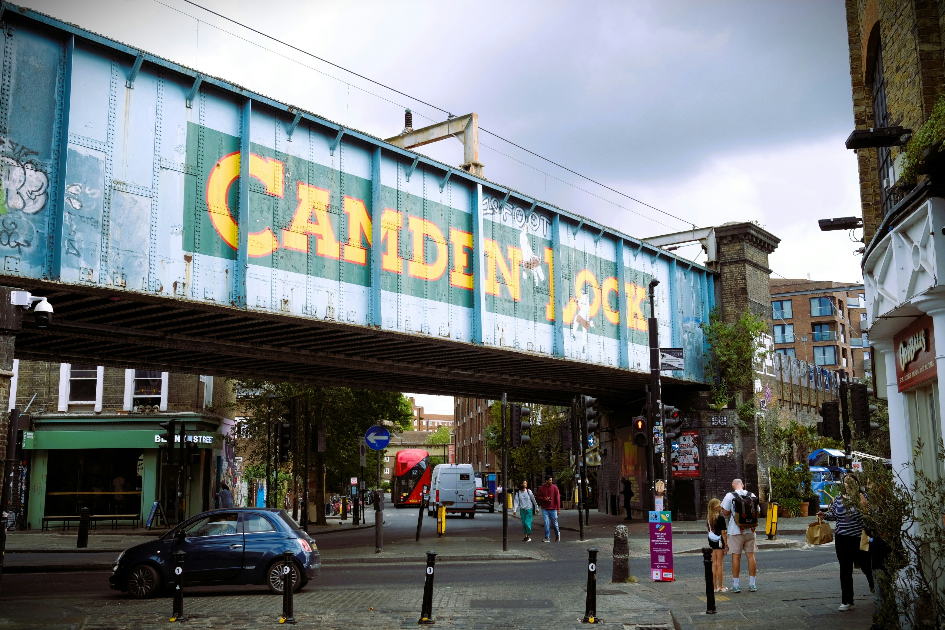 Un pont ferroviaire bleu avec une signalisation de l’écluse de Camden au-dessus d’une rue animée de Londres