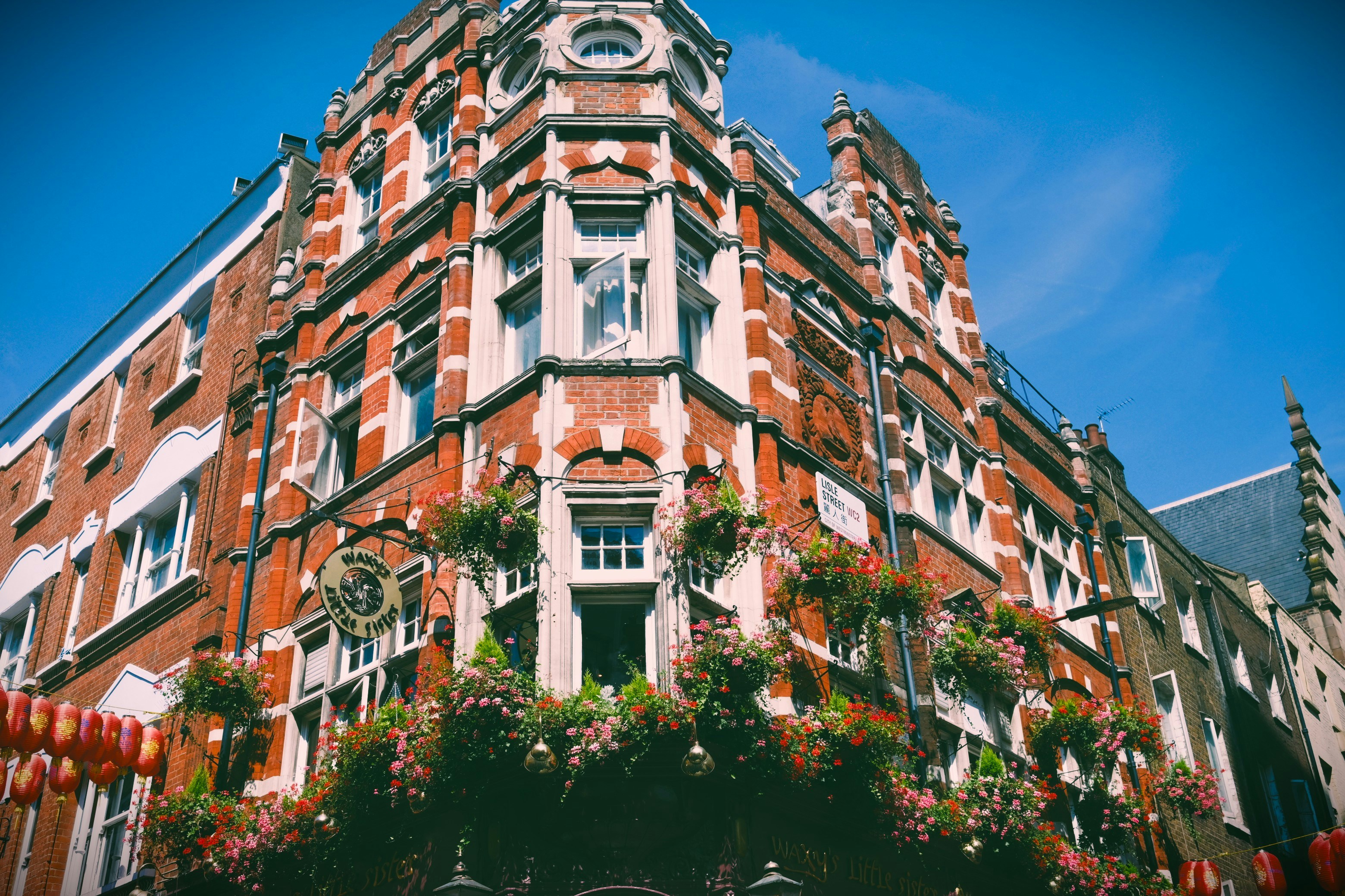 A red brick building with flower-filled window boxes on a street in London