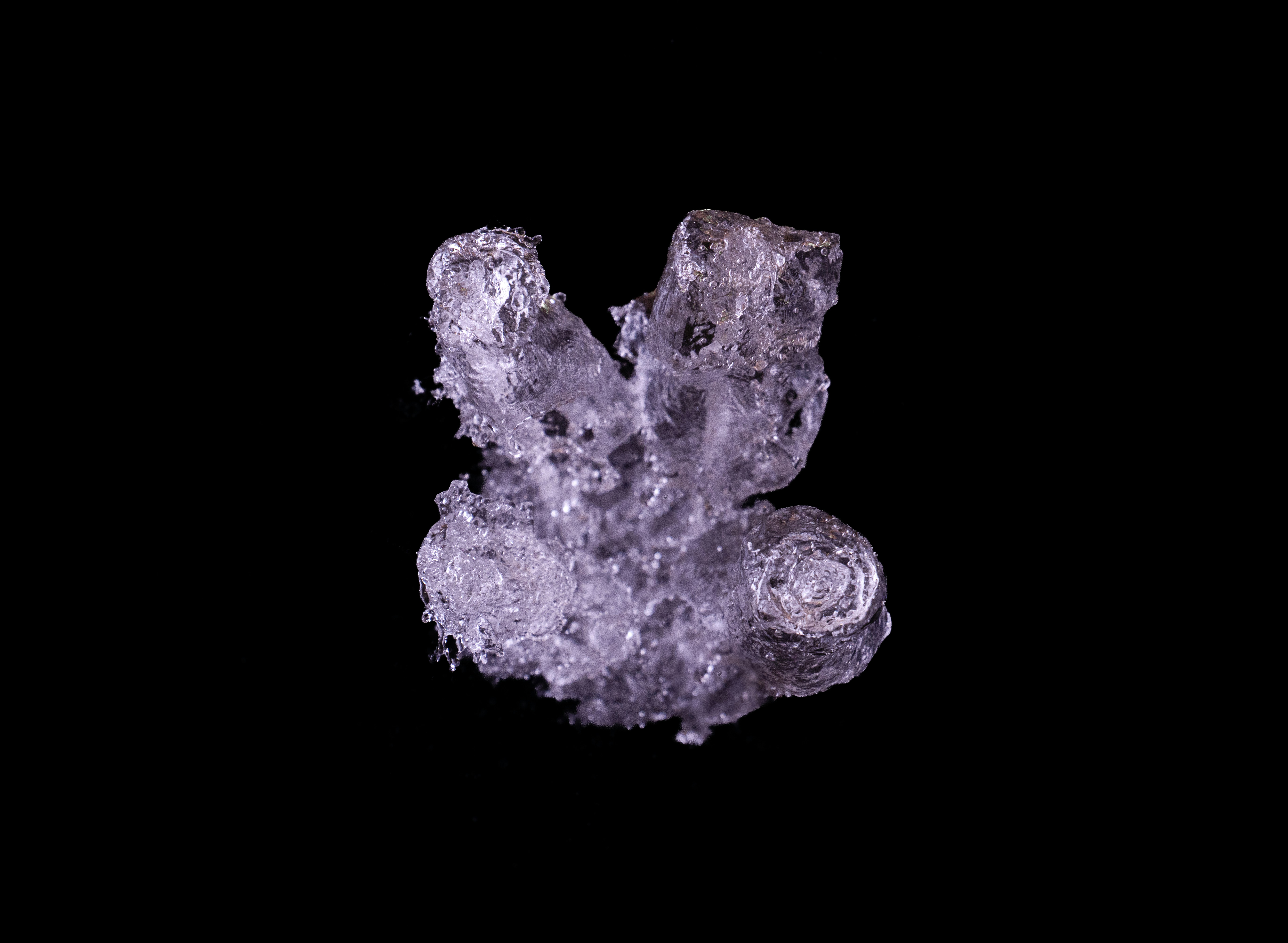 A cluster of translucent ice crystals with jagged edges against a black background.
