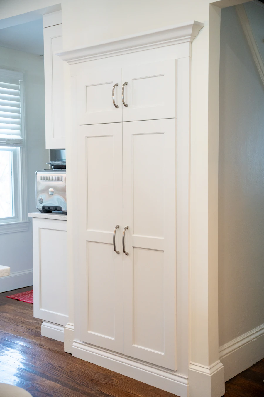 Tall white kitchen pantry cabinet with hardware detail