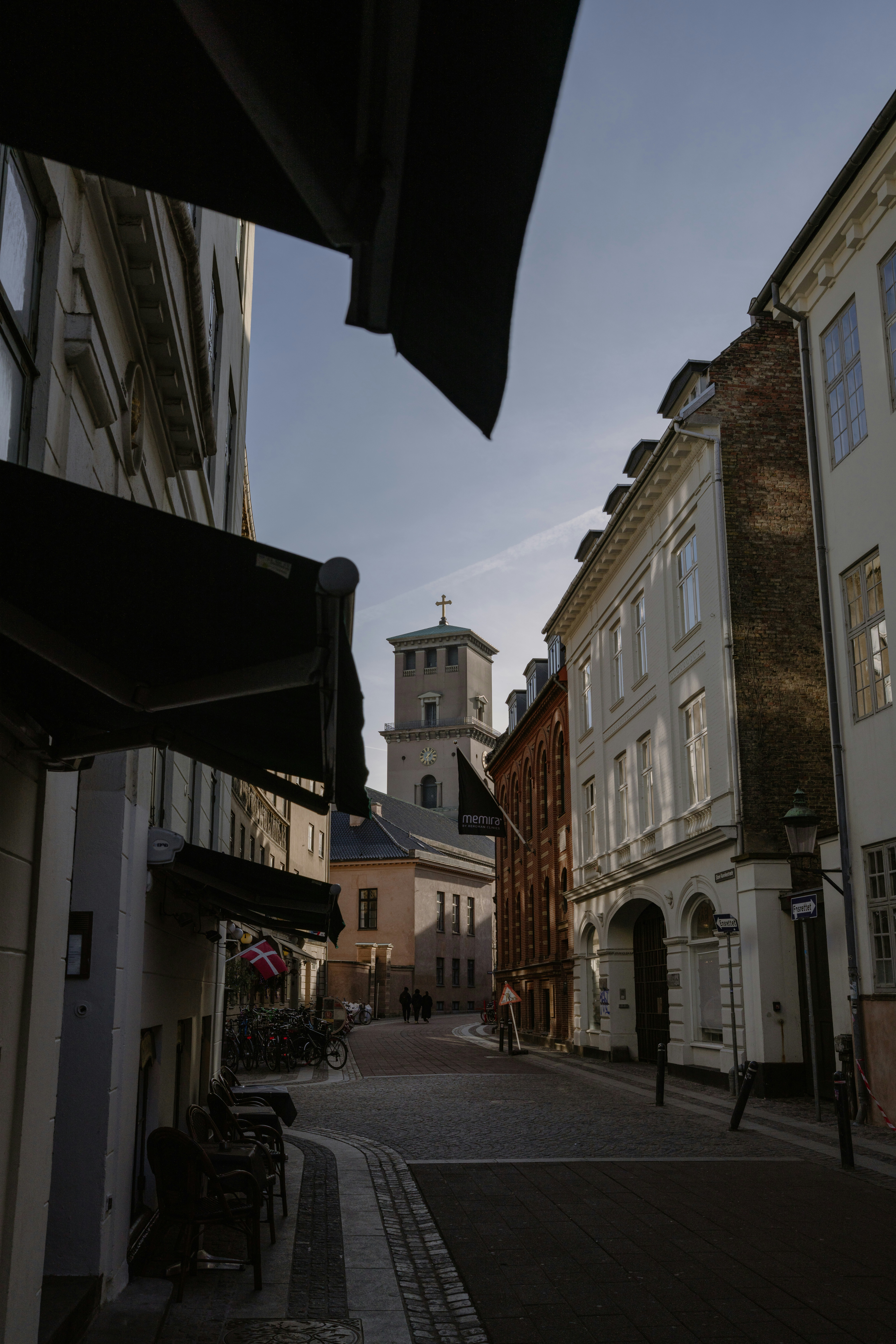 Une rue pavée à Copenhague avec un clocher d’église au loin