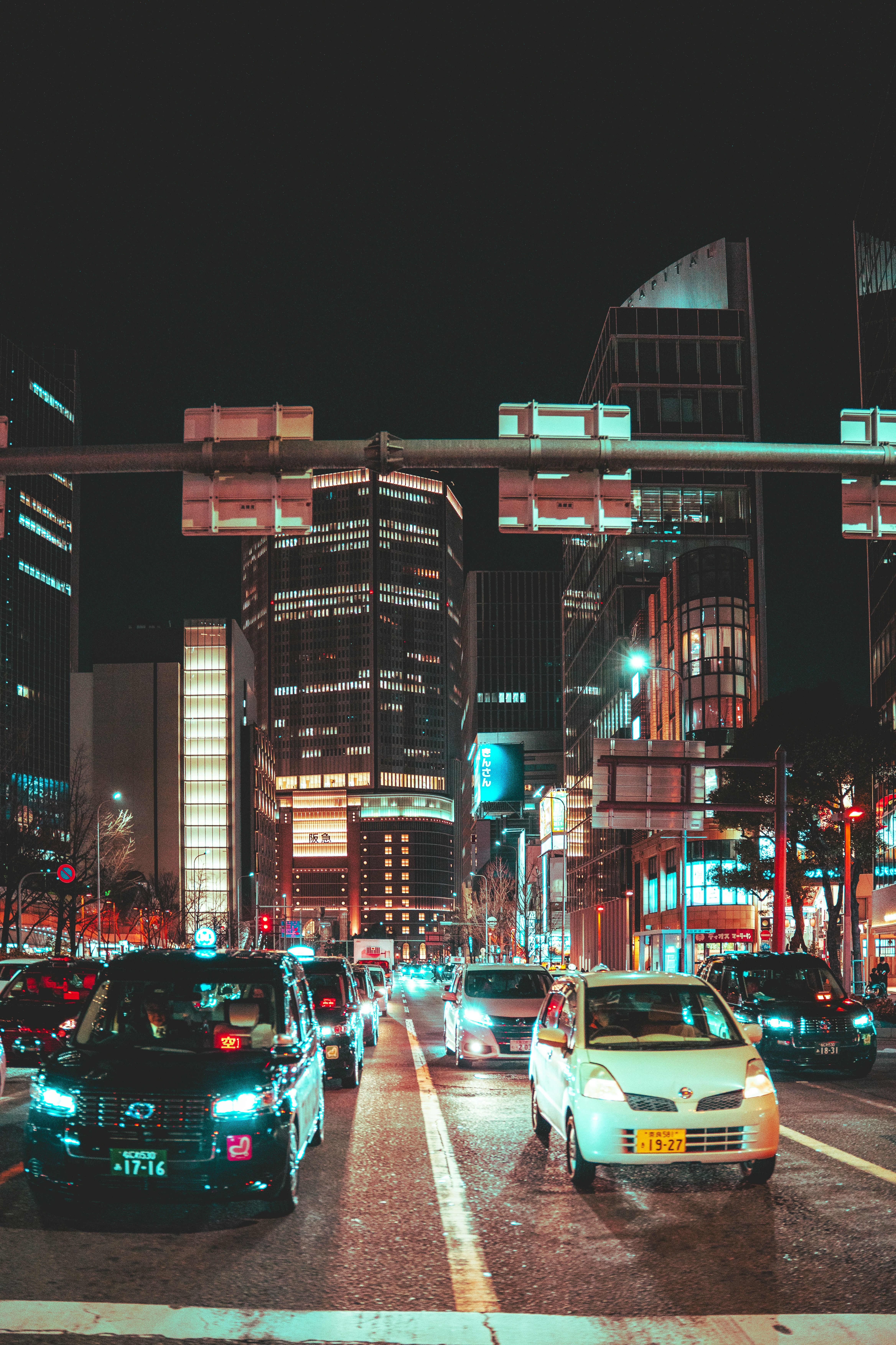 Cars and taxis driving on a city street at night in Osaka, Japan.