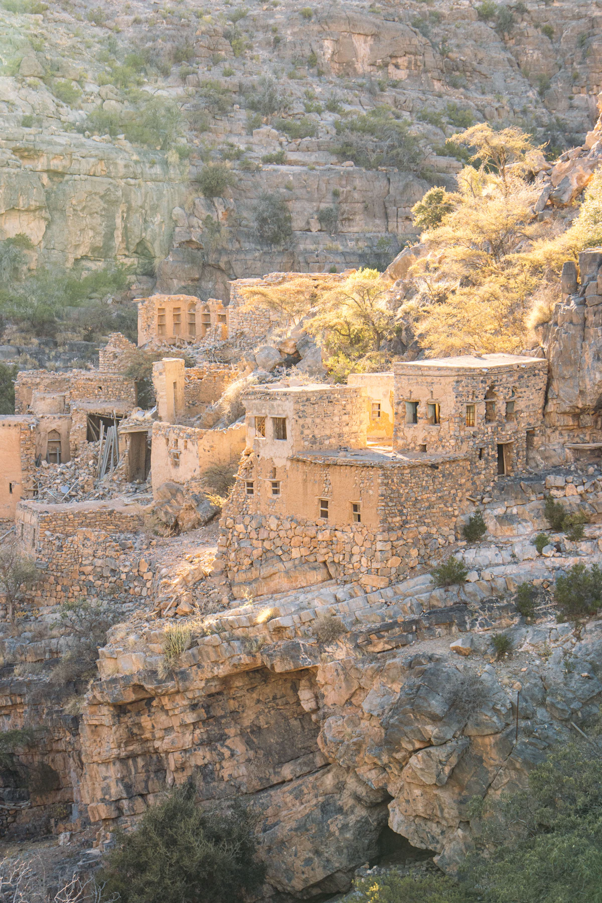 Abandoned stone houses on a cliff ledge in a wadi on Jebel Akhdar