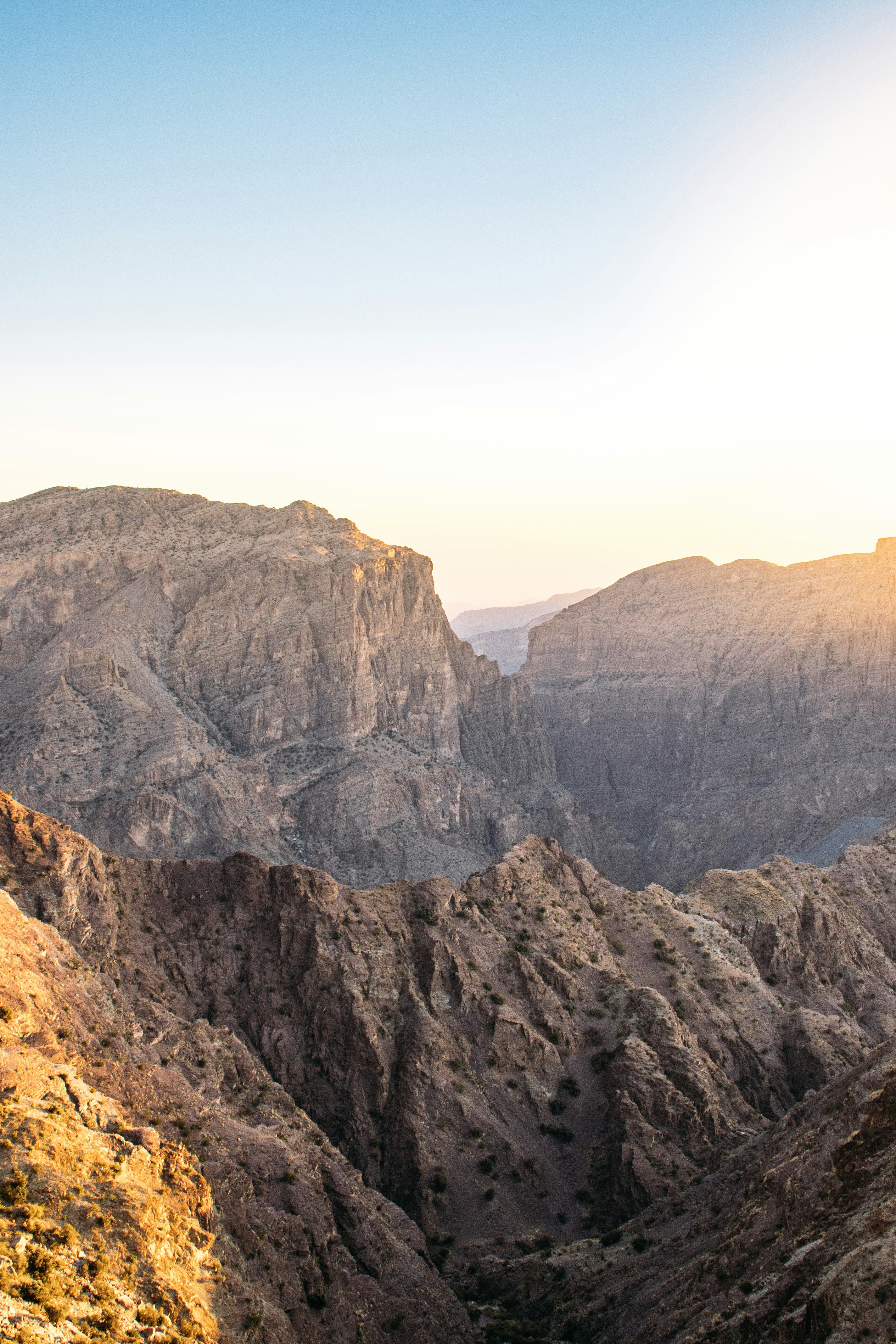Rugged rocky mountains under a bright sky with warm low sun.