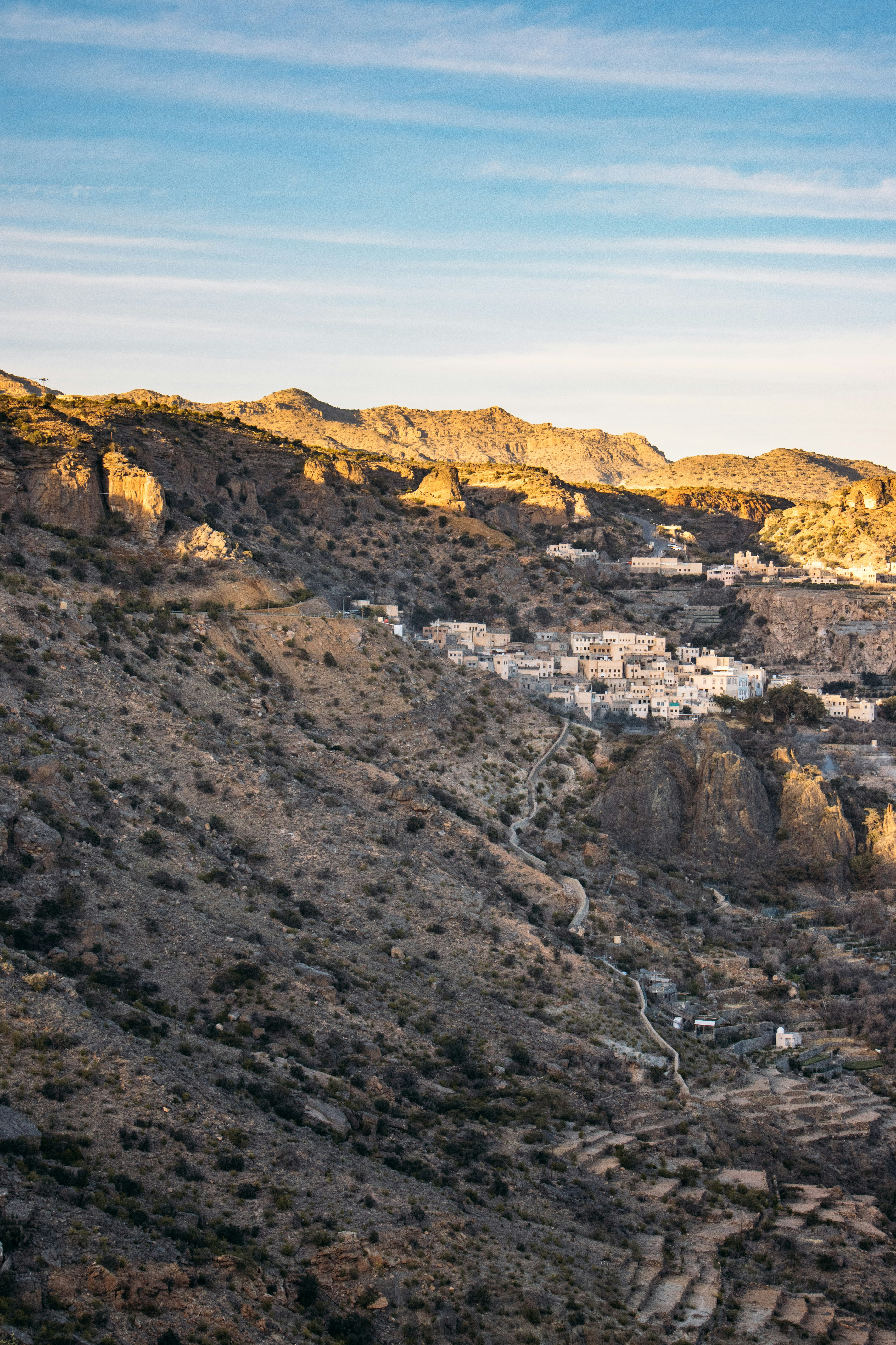 A village nestled in a rocky mountain valley under a clear blue sky.