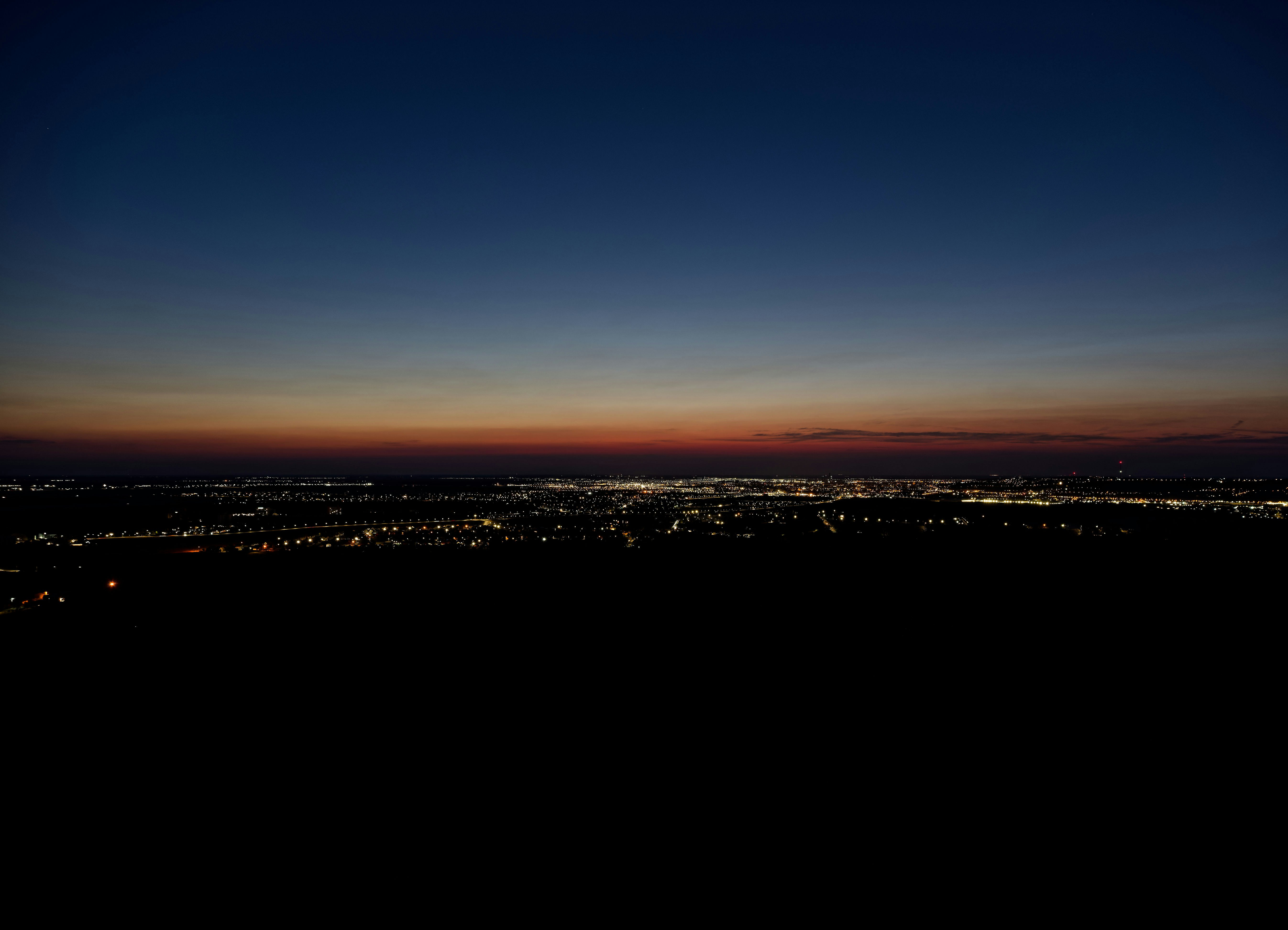 A distant city skyline glowing under a dark blue and orange horizon.