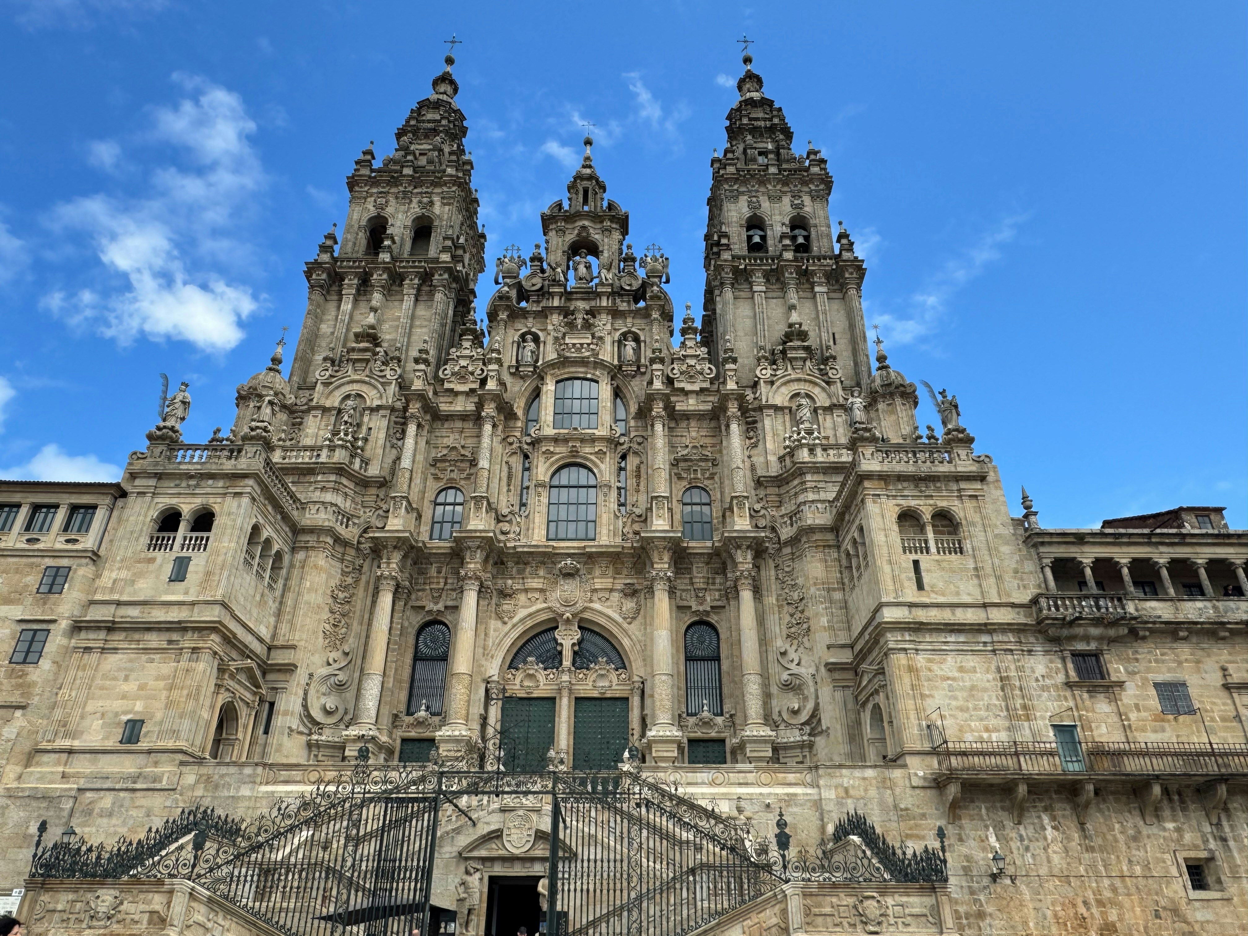 The ornate stone facade of the Cathedral of Santiago de Compostela under a blue sky.