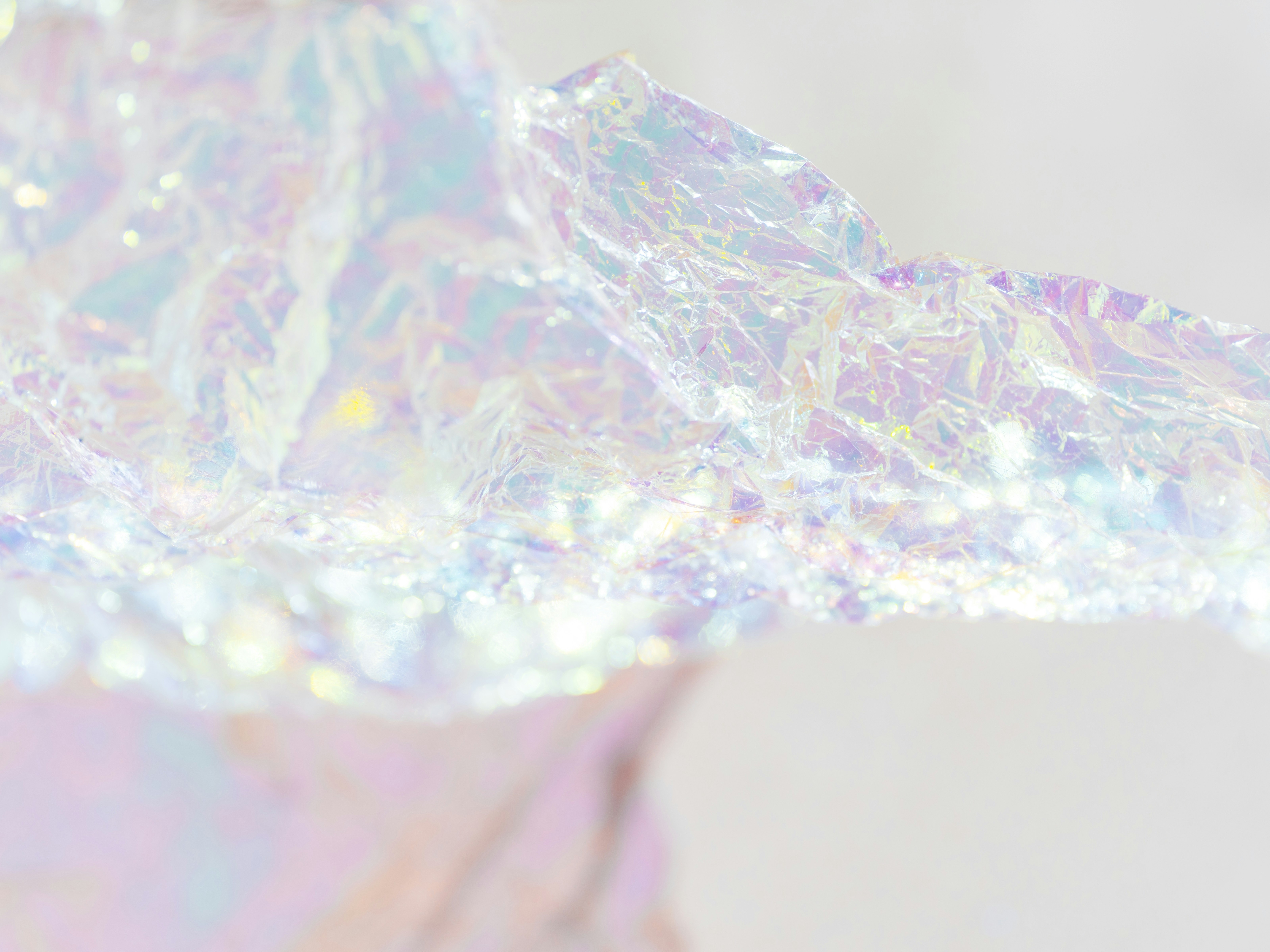 Crumpled iridescent wrapping paper with soft bokeh highlights on a light background