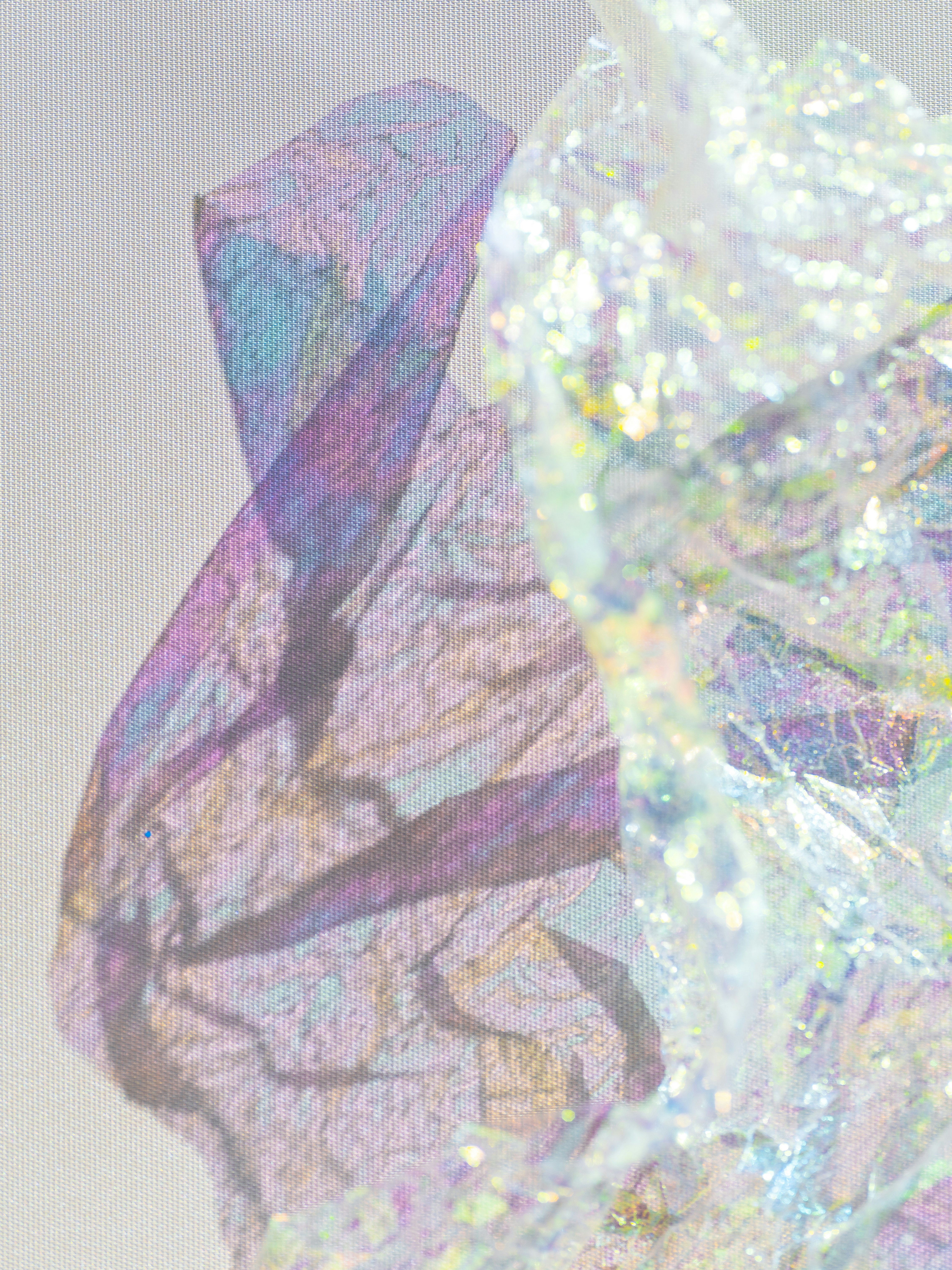 Crumpled iridescent wrapping paper casting a purple shadow on a textured fabric background.