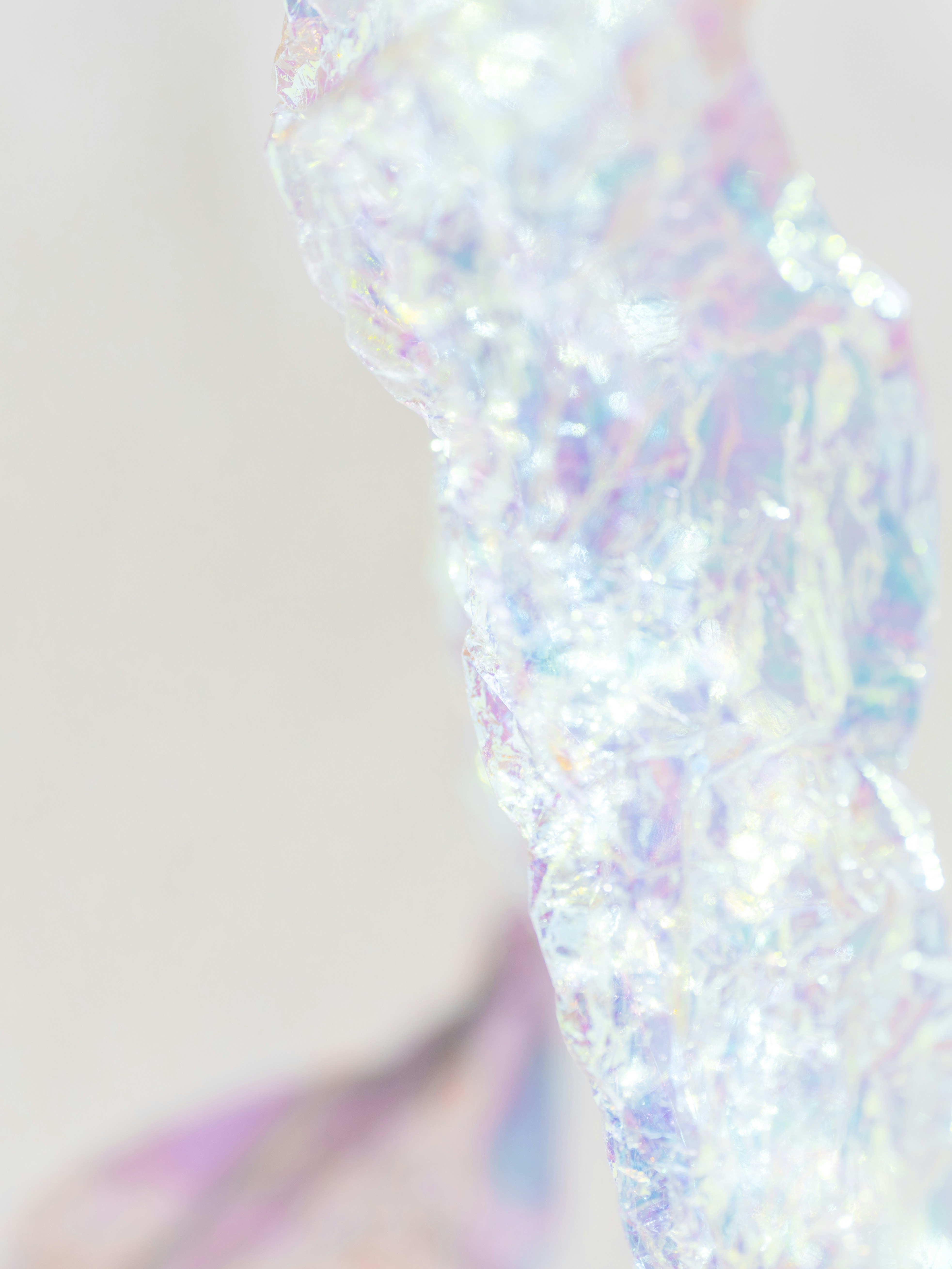 Crumpled iridescent wrapping paper against a soft white cloth background with bokeh.