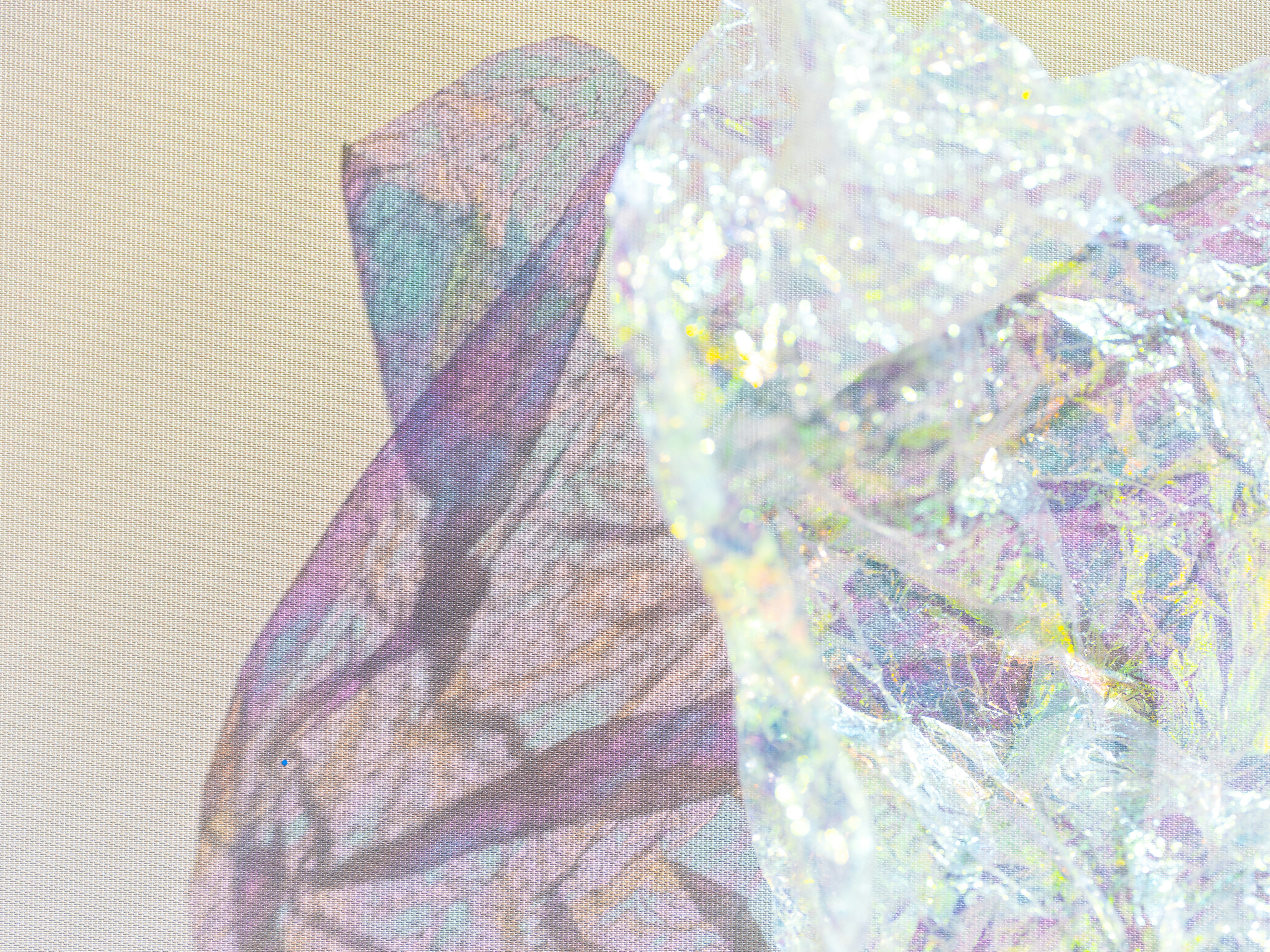 Crumpled iridescent wrapping paper casting a purple shadow on a beige fabric background