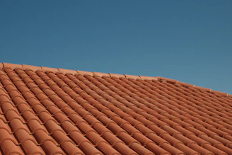 Red clay roof tiles against a clear blue sky