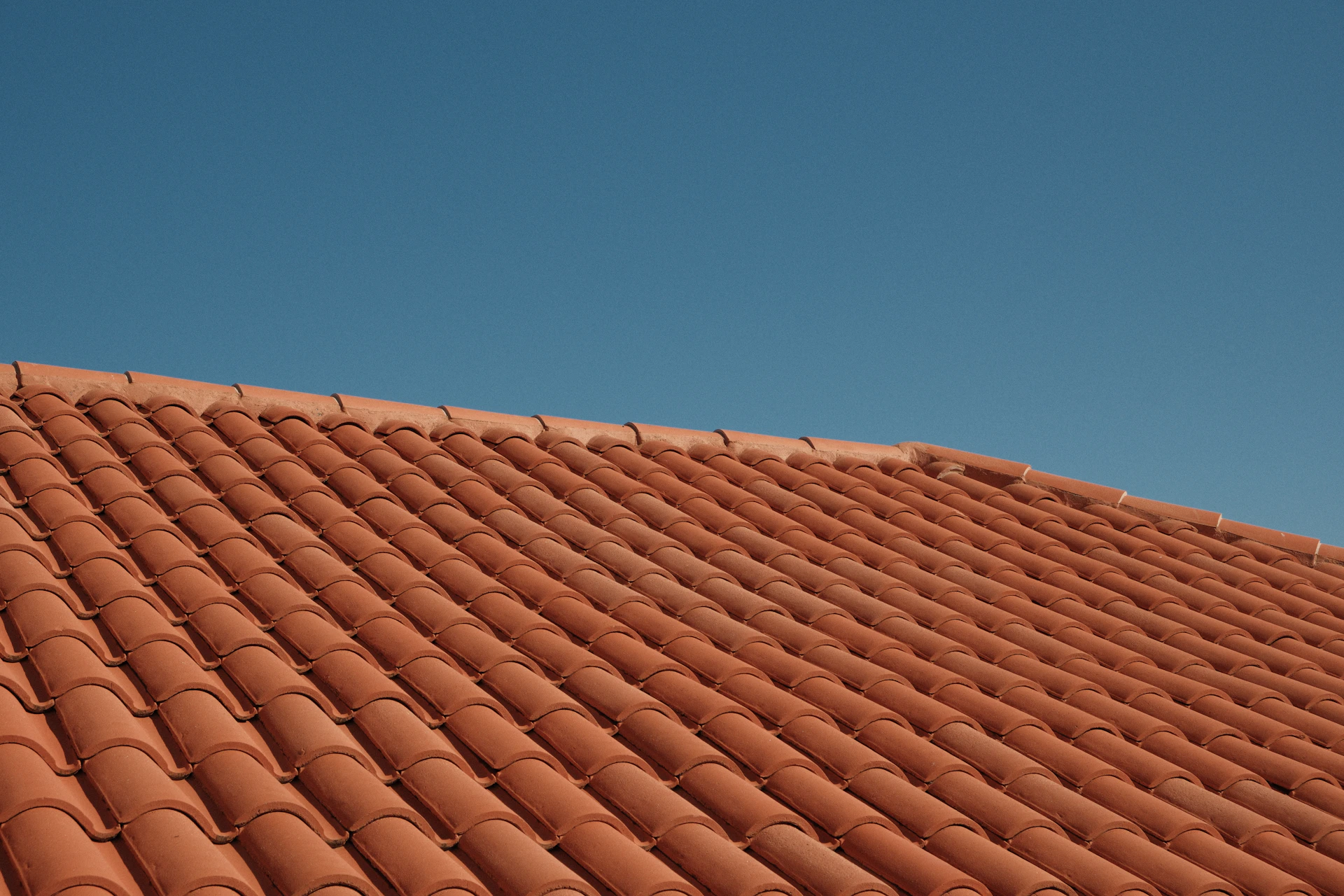 Red clay roof tiles against a clear blue sky