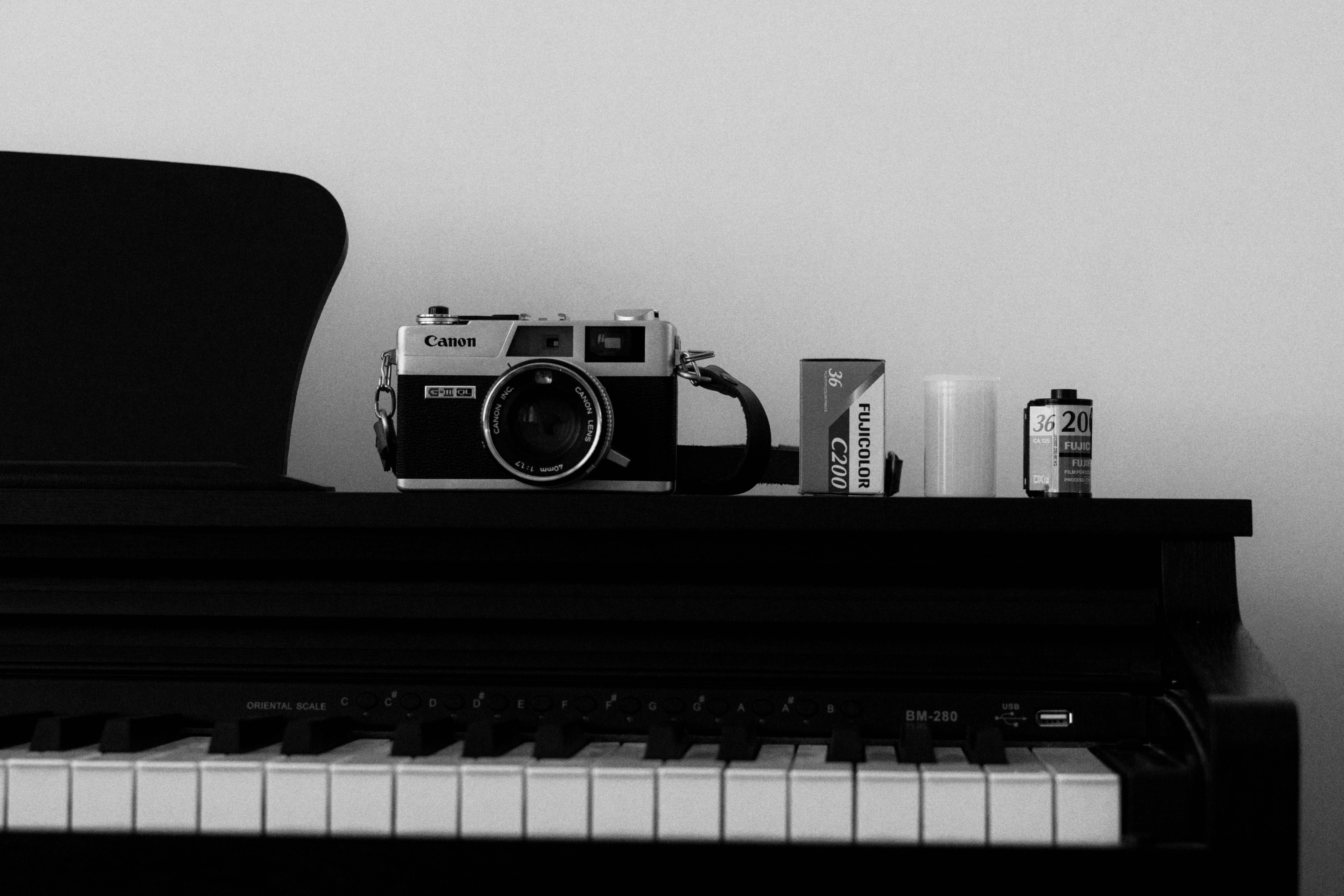 ヴィンテージのフィルムカメラと黒いピアノに2本のフィルムが入っています