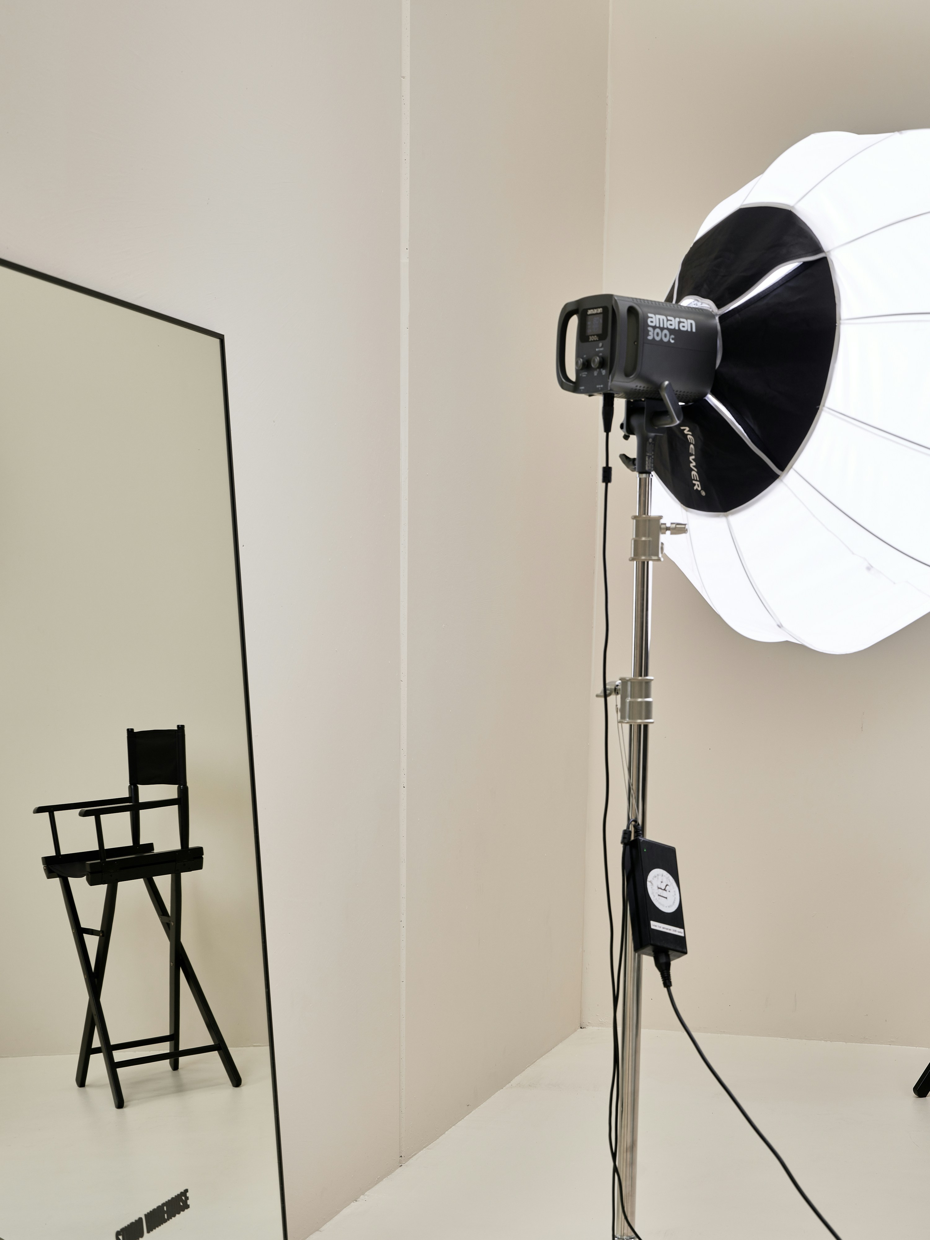 Lampu studio besar dengan softbox dan cermin yang memantulkan kursi sutradara