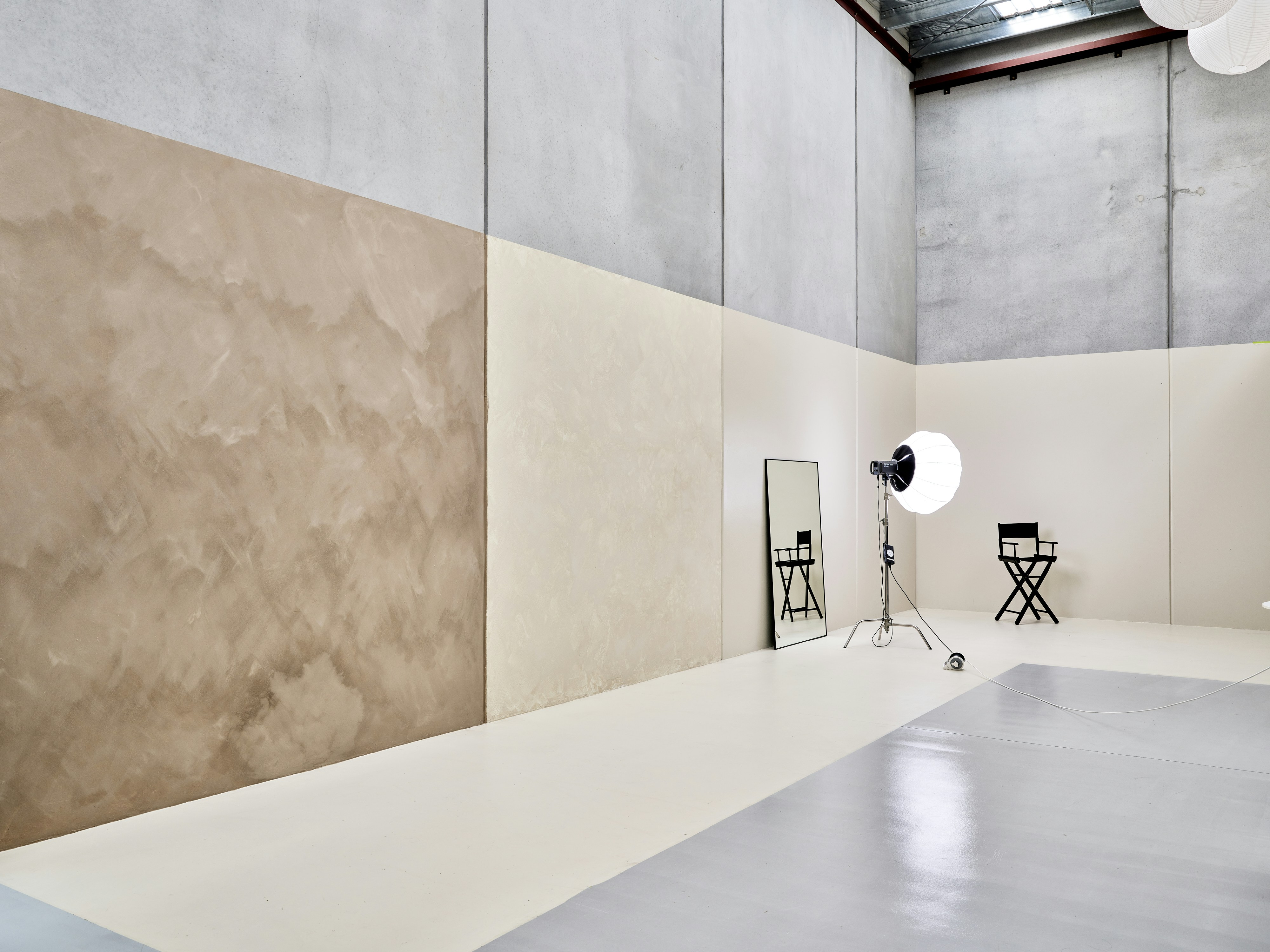 Ein Fotostudio mit Betonwänden, einem Spiegel und einem Regiestuhl.